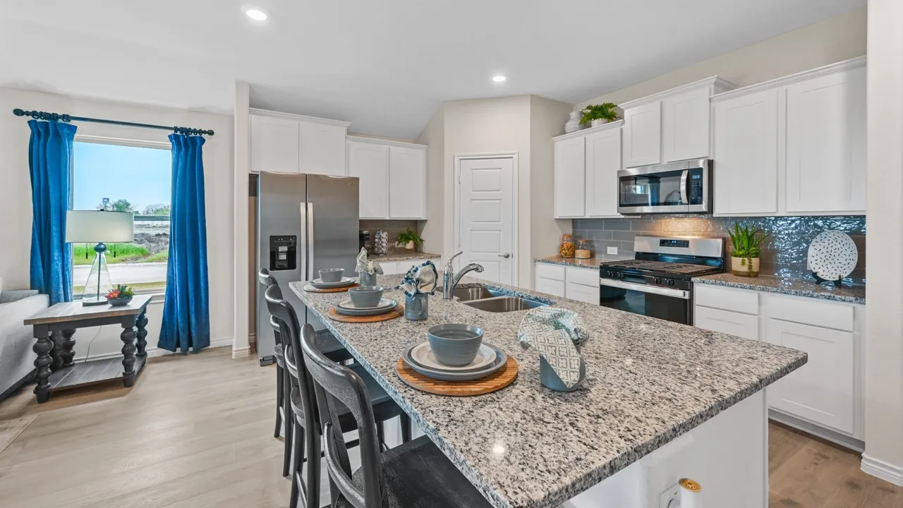 Kitchen with a breakfast bar, stainless steel appliances, white cabinets, light wood-style floors, and light stone counters
