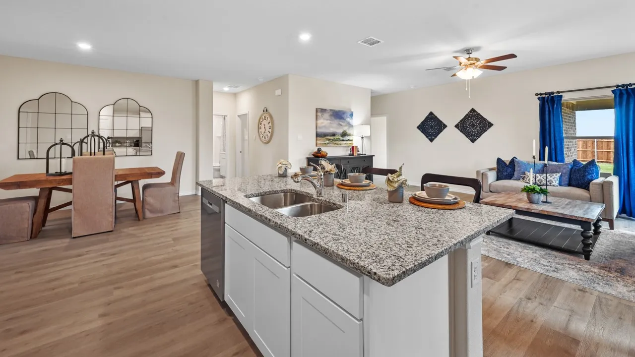 Kitchen with open floor plan, white cabinets, light stone countertops, light wood finished floors, and a center island with sink