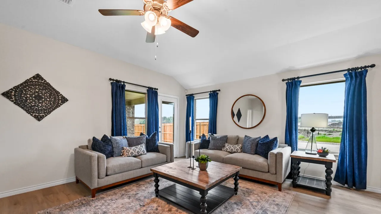 Living area with light wood-type flooring, healthy amount of natural light, a ceiling fan, and vaulted ceiling