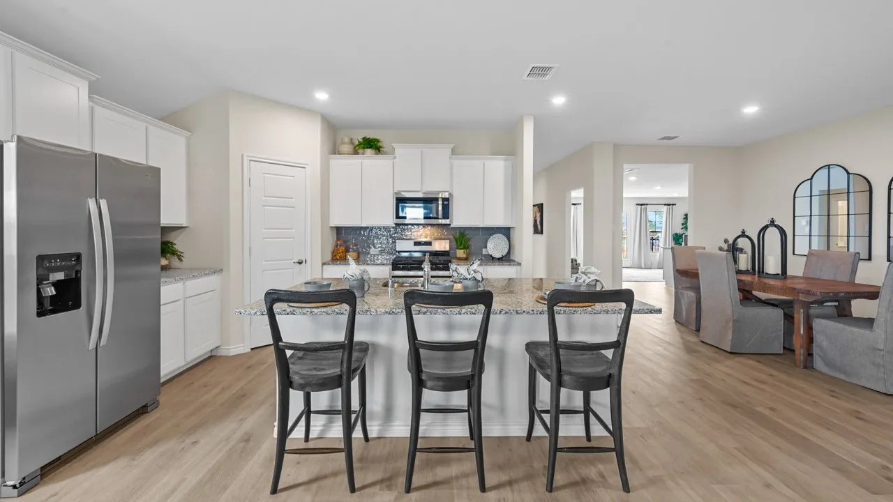 Kitchen featuring stainless steel appliances, white cabinetry, a kitchen island with sink, a breakfast bar, and light wood-style flooring