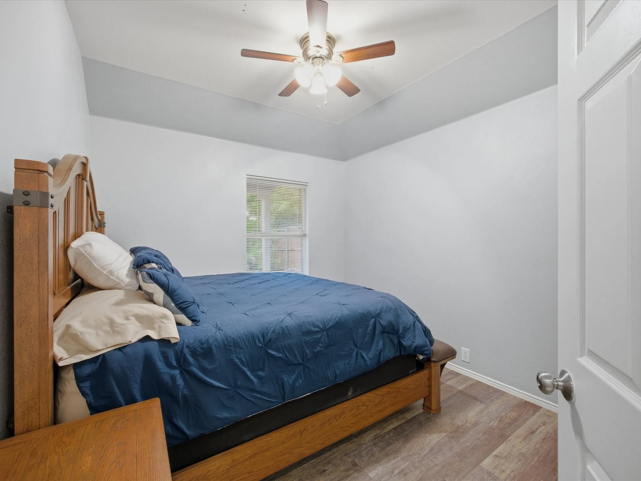 Bedroom  1 with light wood-style floors, ceiling fan, and vaulted ceiling