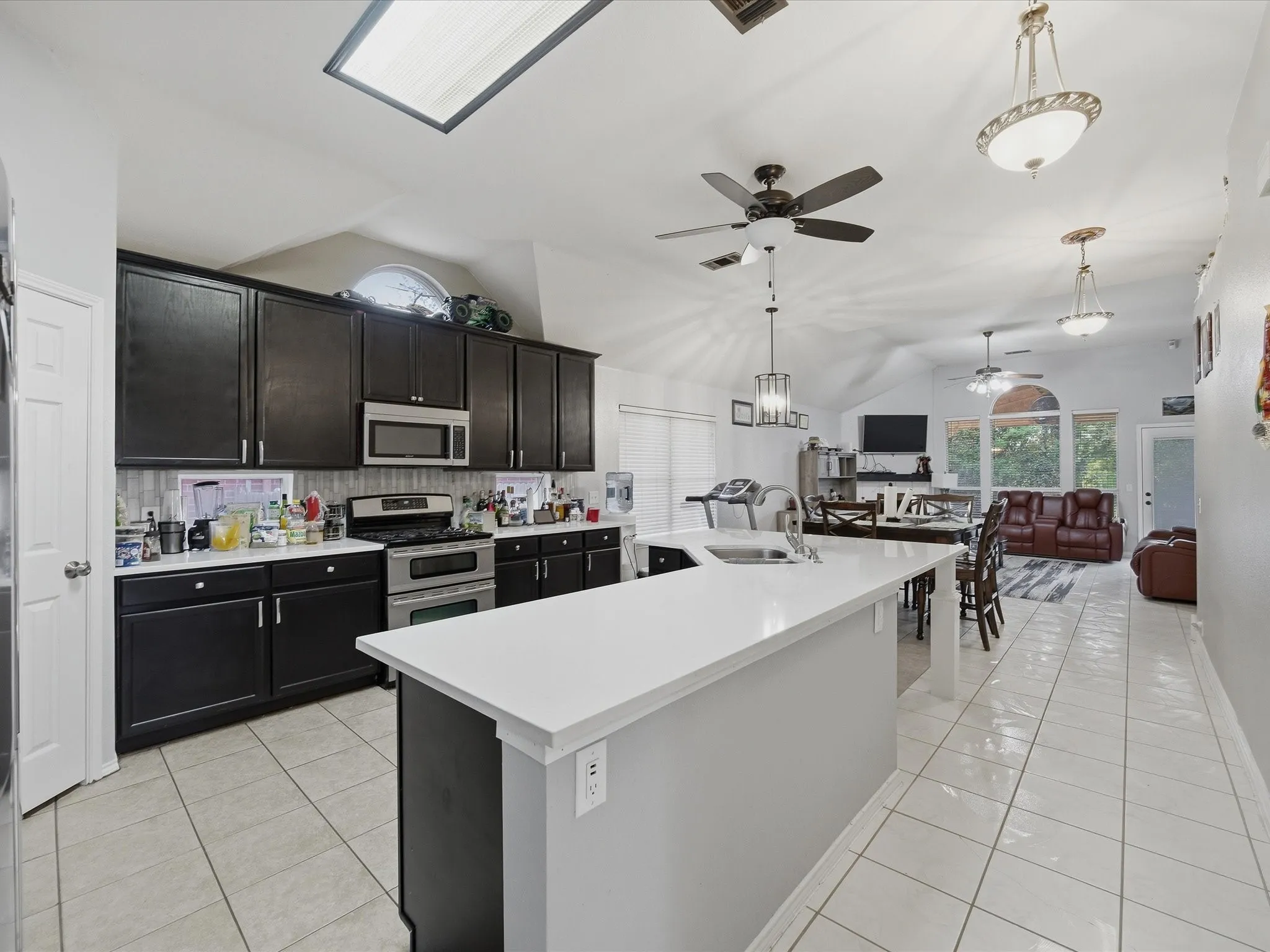 Kitchen featuring ceiling fan, vaulted ceiling, light countertops, and stainless steel appliances