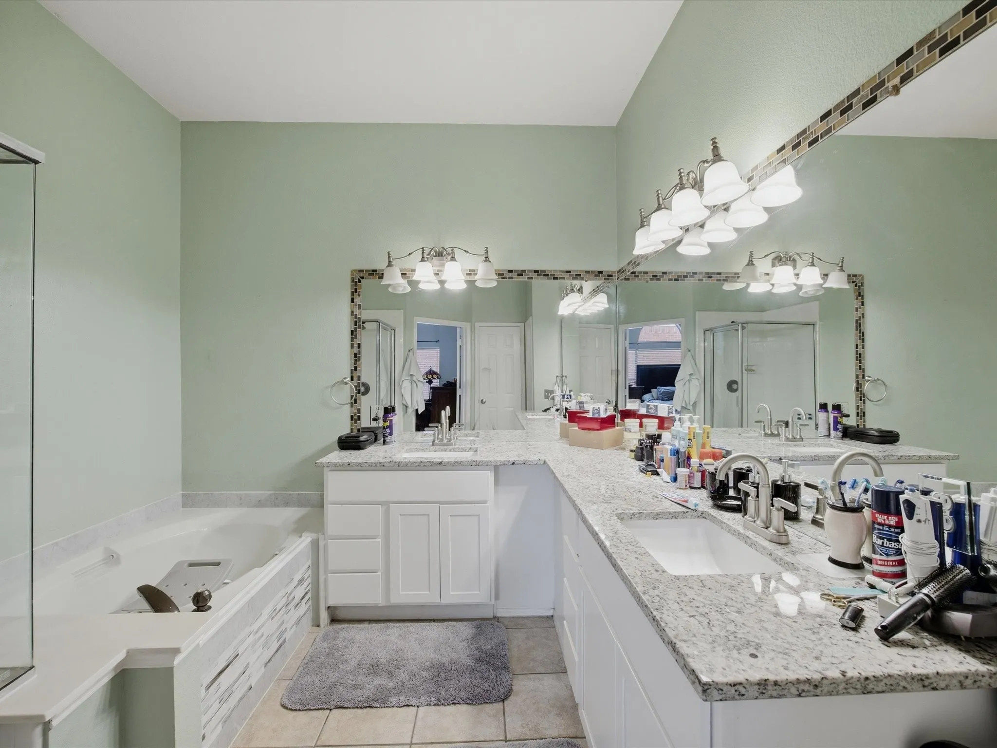 Master Bathroom featuring double vanity, light tile patterned floors, a garden tub, and a shower stall