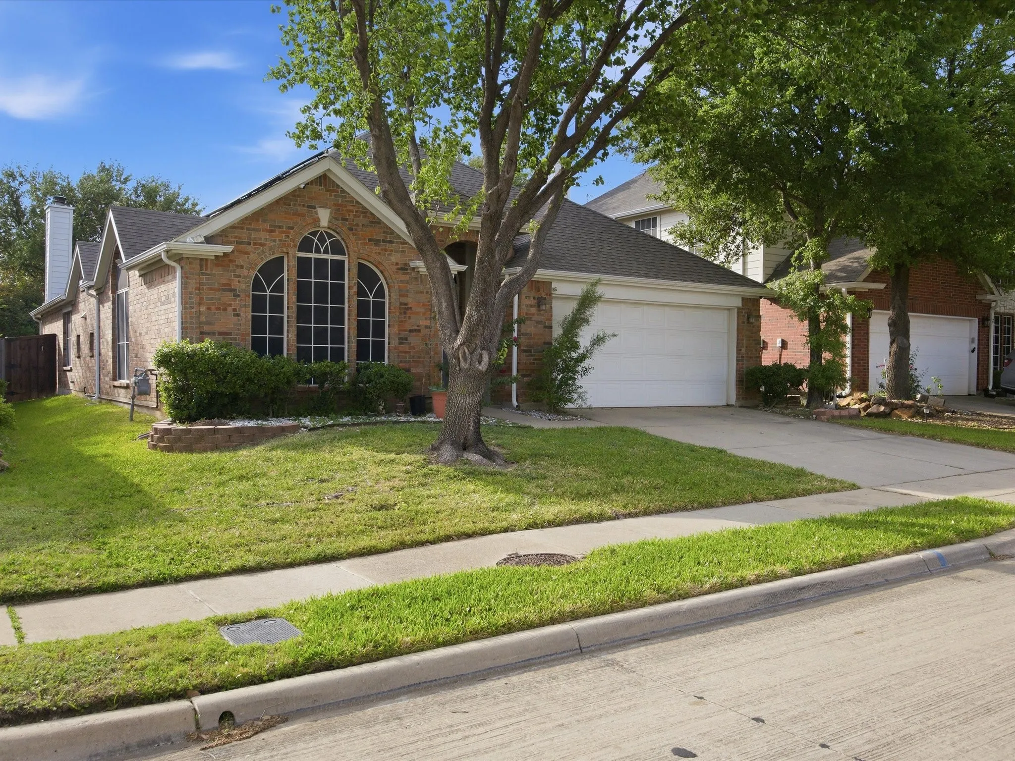 View of front facade featuring a garage, brick siding, driveway, and a front yard