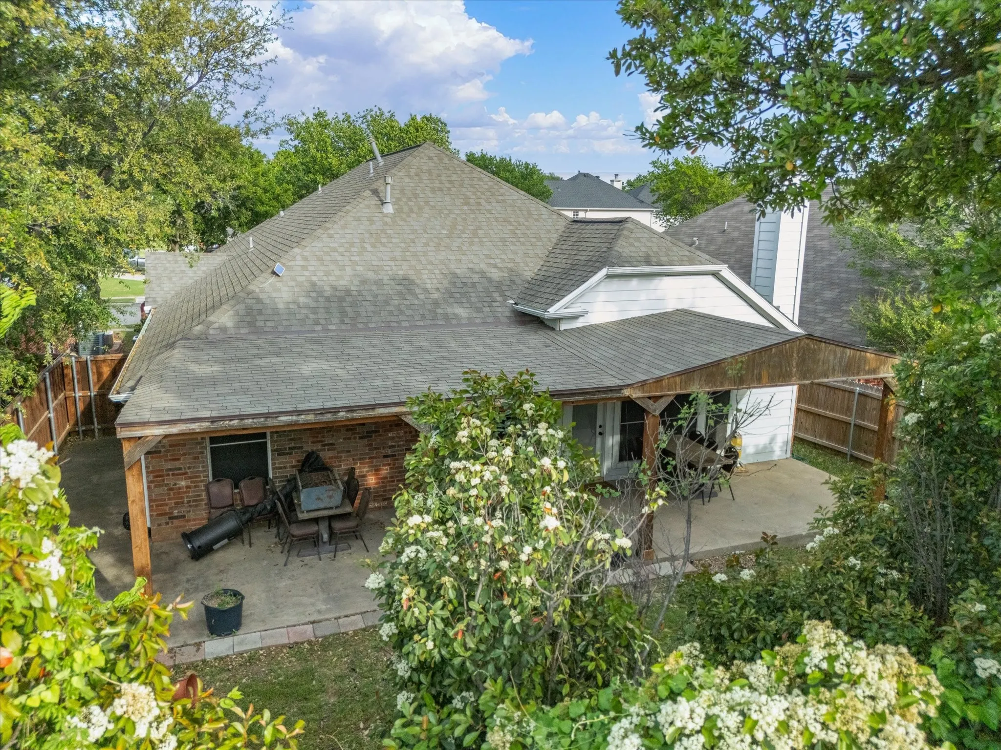Rear view of house with a patio, a shingled roof, a chimney, and brick siding