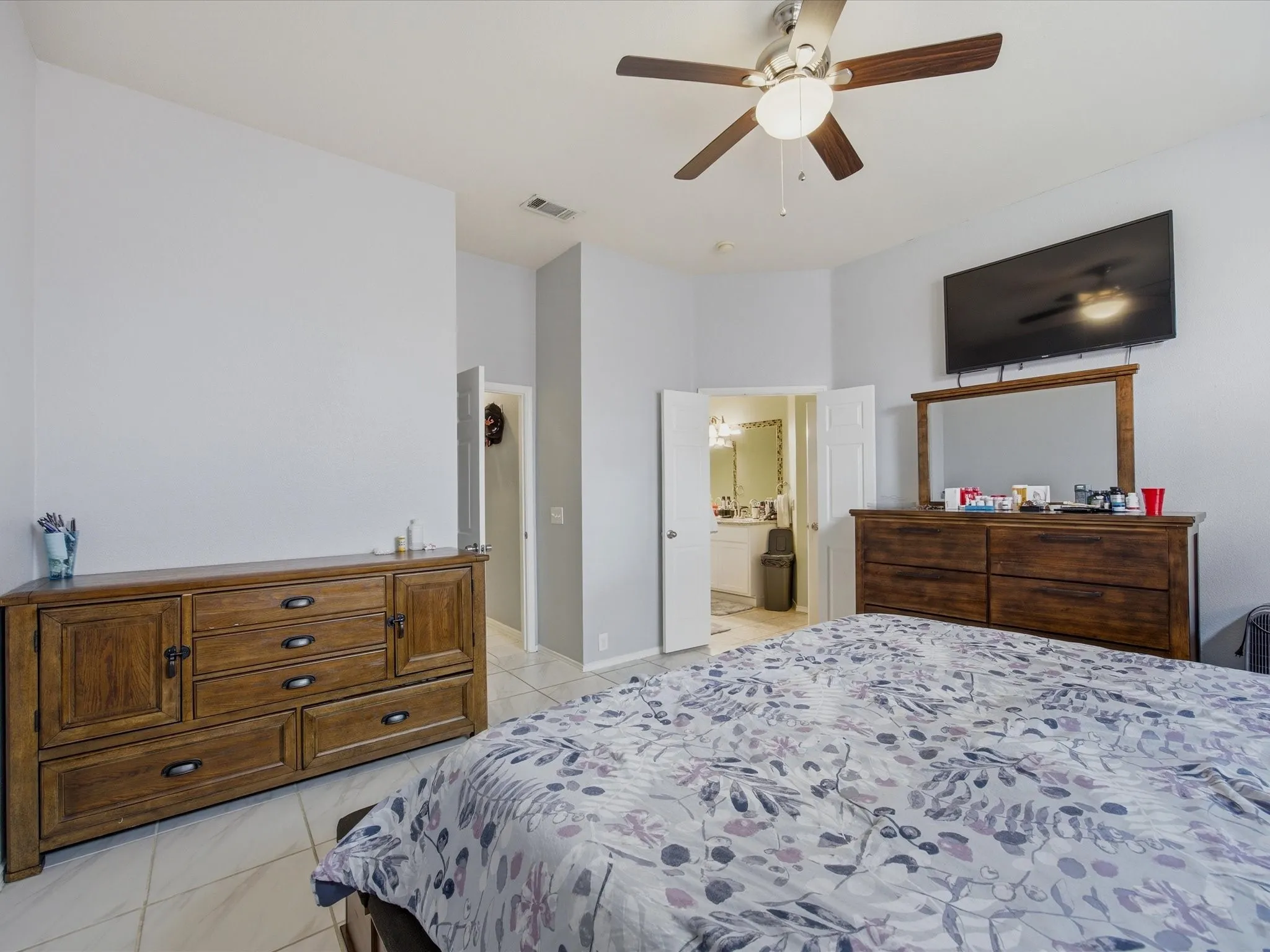 Master Bedroom featuring light tile patterned flooring, a ceiling fan, and connected bathroom