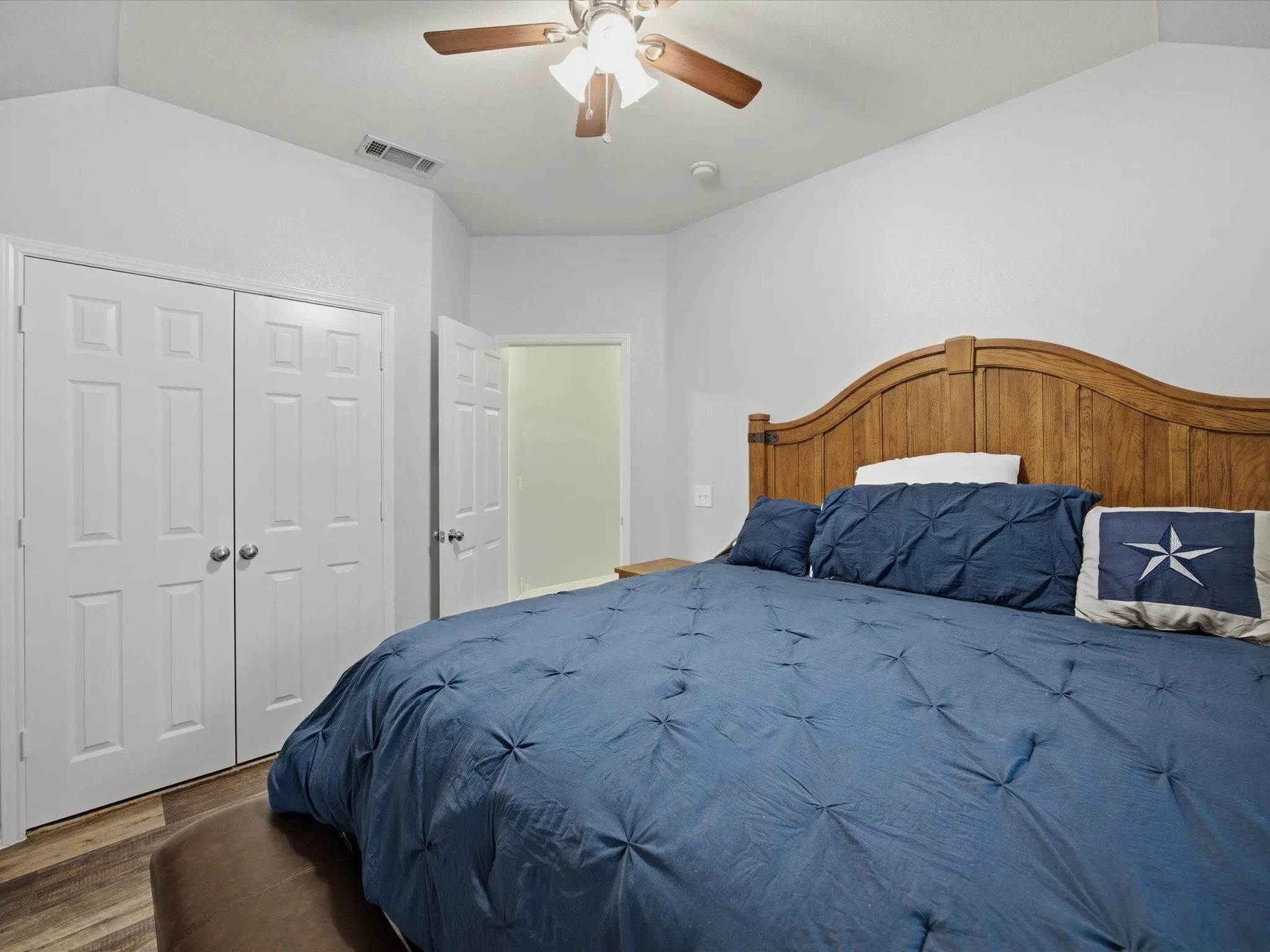Bedroom 1 with lofted ceiling, a closet, a ceiling fan, and wood finished floors
