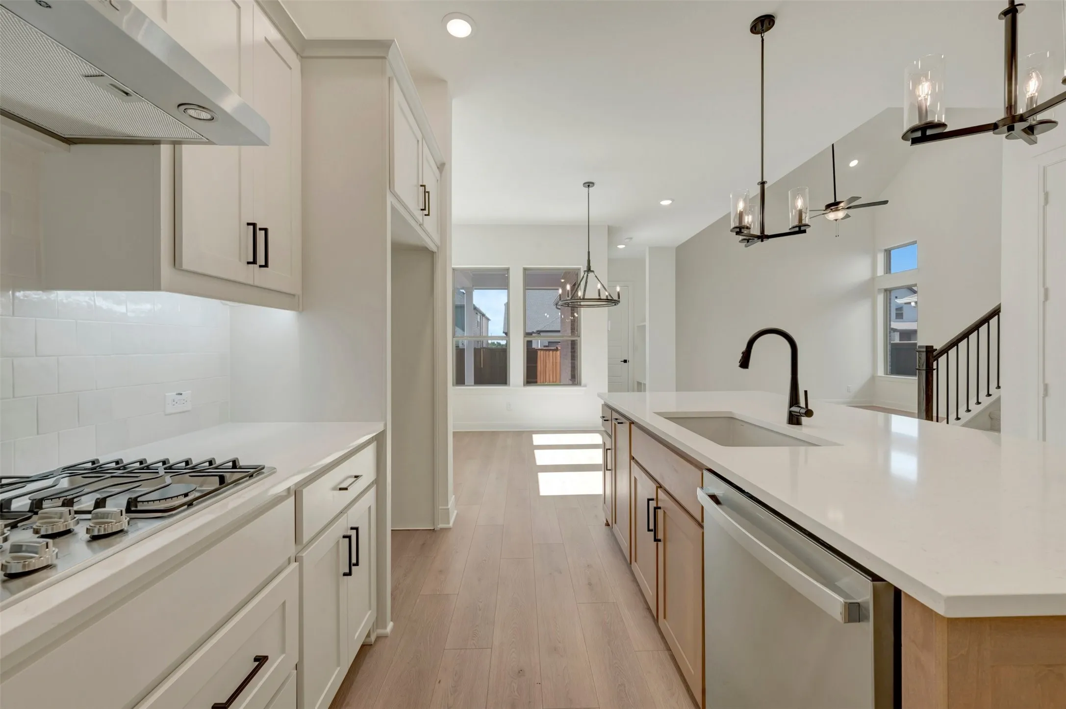 Kitchen featuring white cabinetry, subway tile backsplash, a gas cooktop, and an island with an undermount sink and a matte black faucet