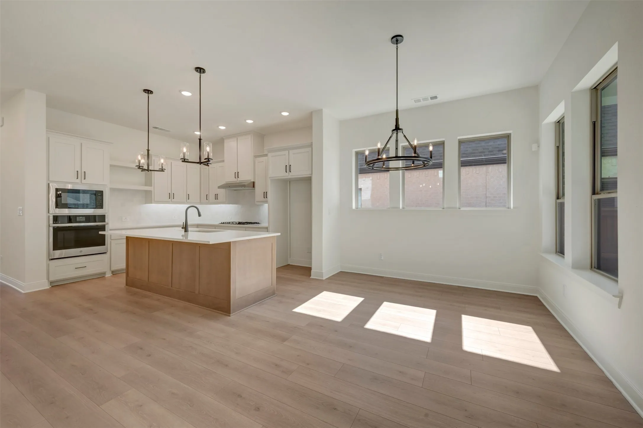Open-concept kitchen and dining area featuring light wood-finish flooring