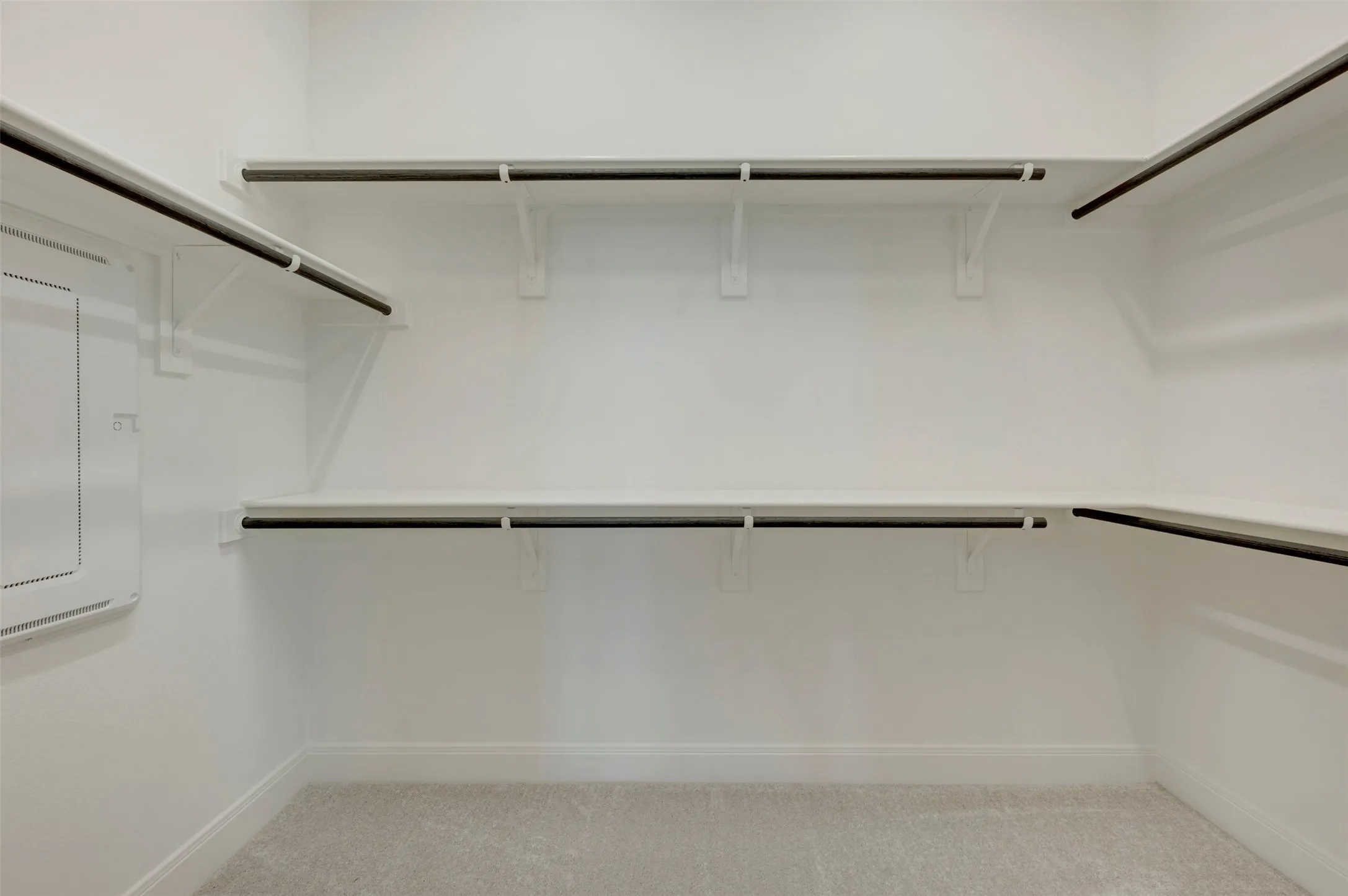 Spacious walk-in closet featuring white painted shelving and dark-finish hanging rods