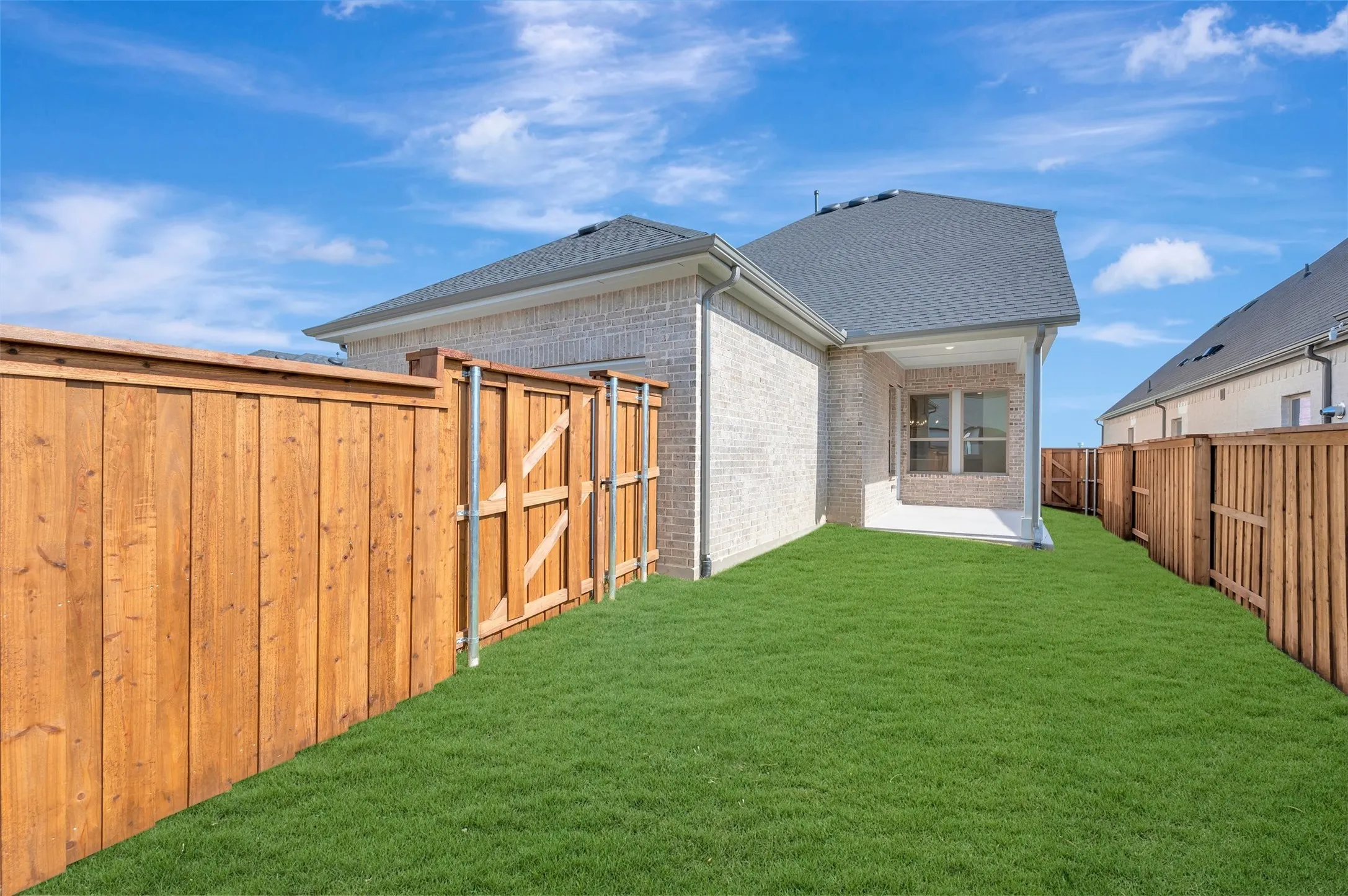 Expansive private yard featuring a manicured lawn, full wood fencing, and a covered concrete patio