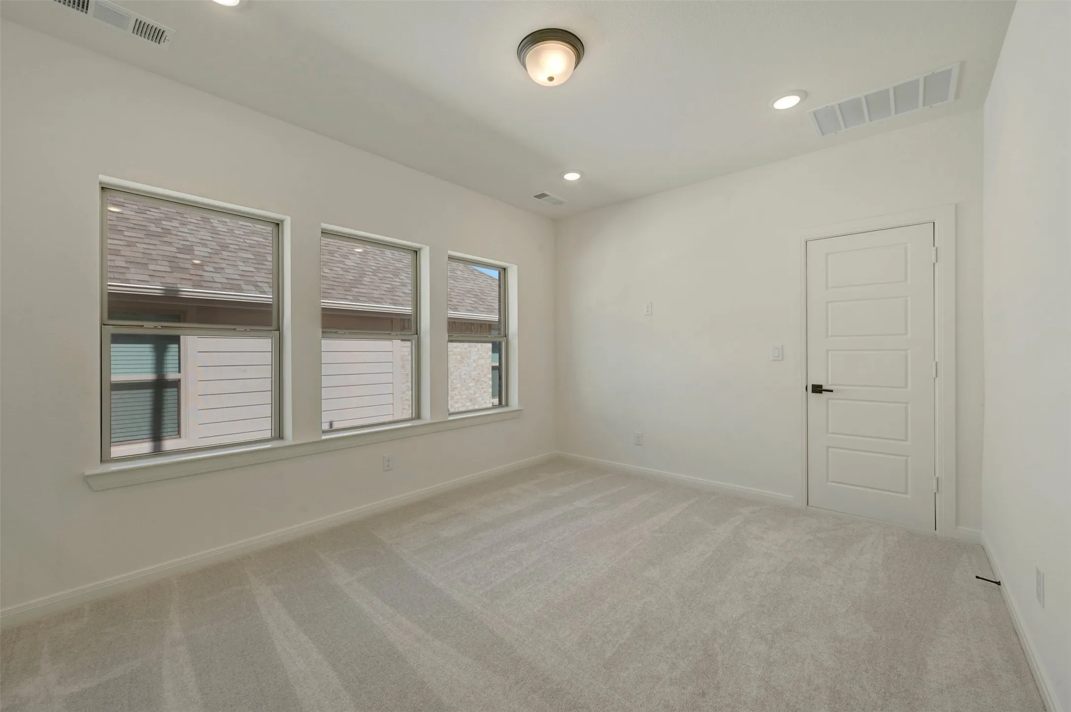 Spacious room featuring light-toned carpeting and multiple windows