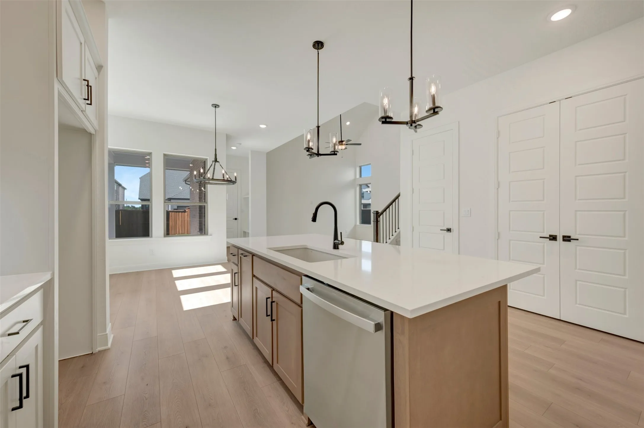 Kitchen island featuring a single-basin sink with matte black faucet, integrated dishwasher, and light-toned cabinetry