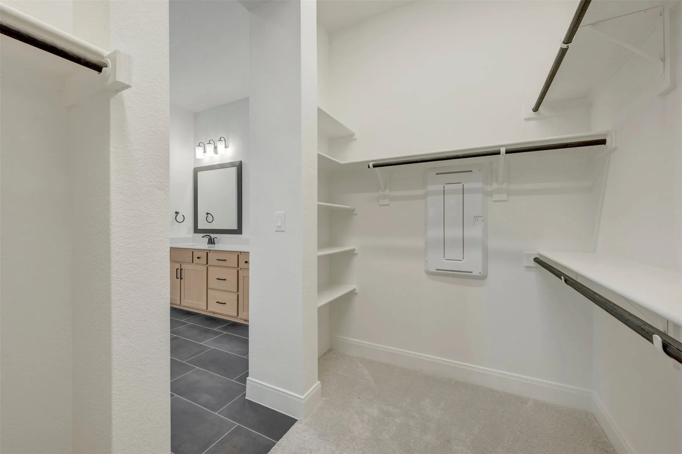 Walk-in closet featuring white shelving, hanging rods, and light-toned carpeting