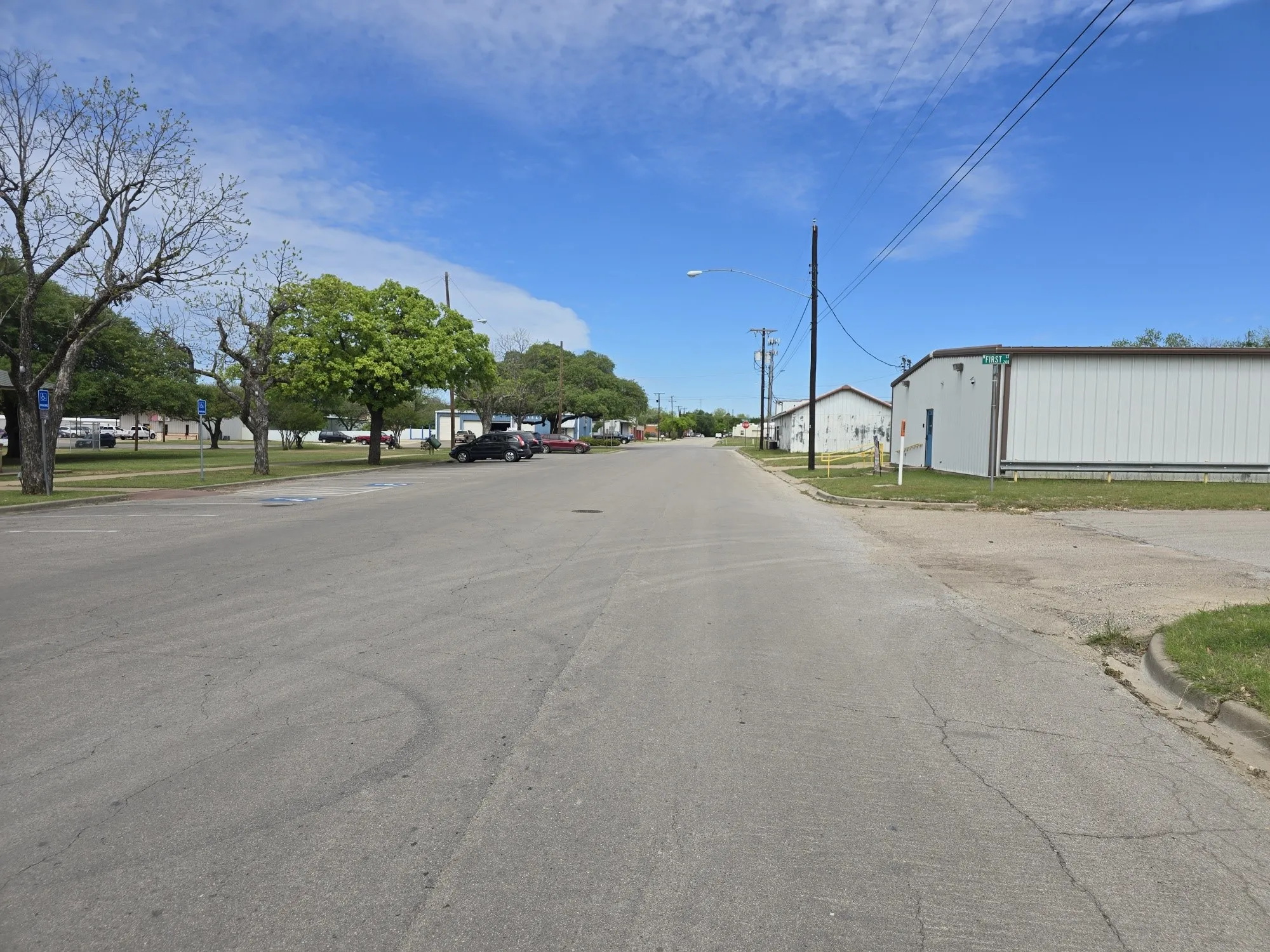 View of asphalt street with curbs, street lighting, and sidewalks