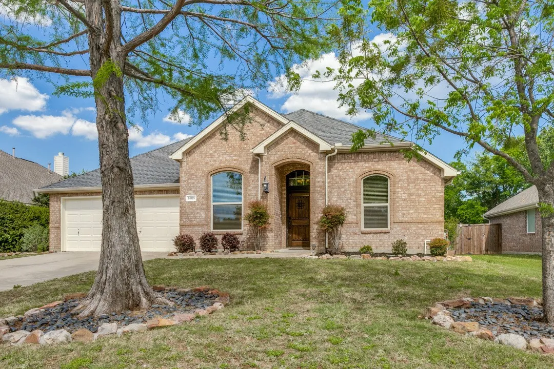 Single story home with brick siding, an attached garage, driveway, and a shingled roof