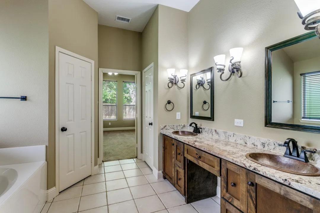 Bathroom featuring double vanity, a garden tub, and light tile patterned flooring