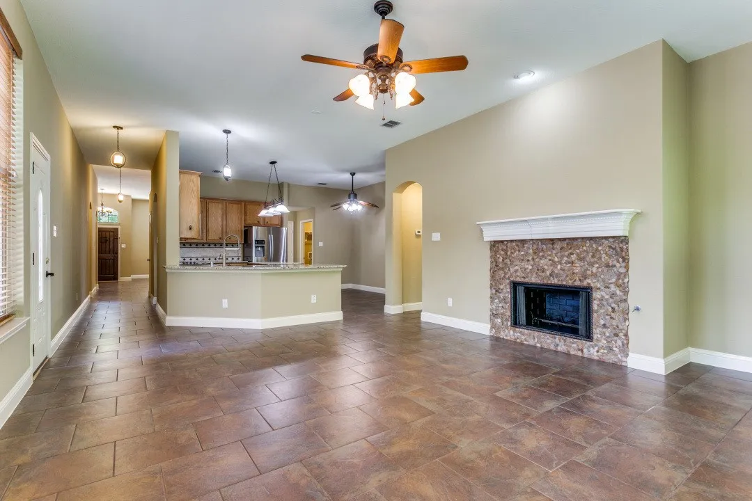 Unfurnished living room featuring a ceiling fan, a fireplace, and arched walkways