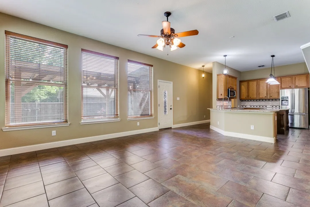 Kitchen featuring a ceiling fan, stainless steel appliances, wood finish cabinets, open floor plan, and hanging light fixtures