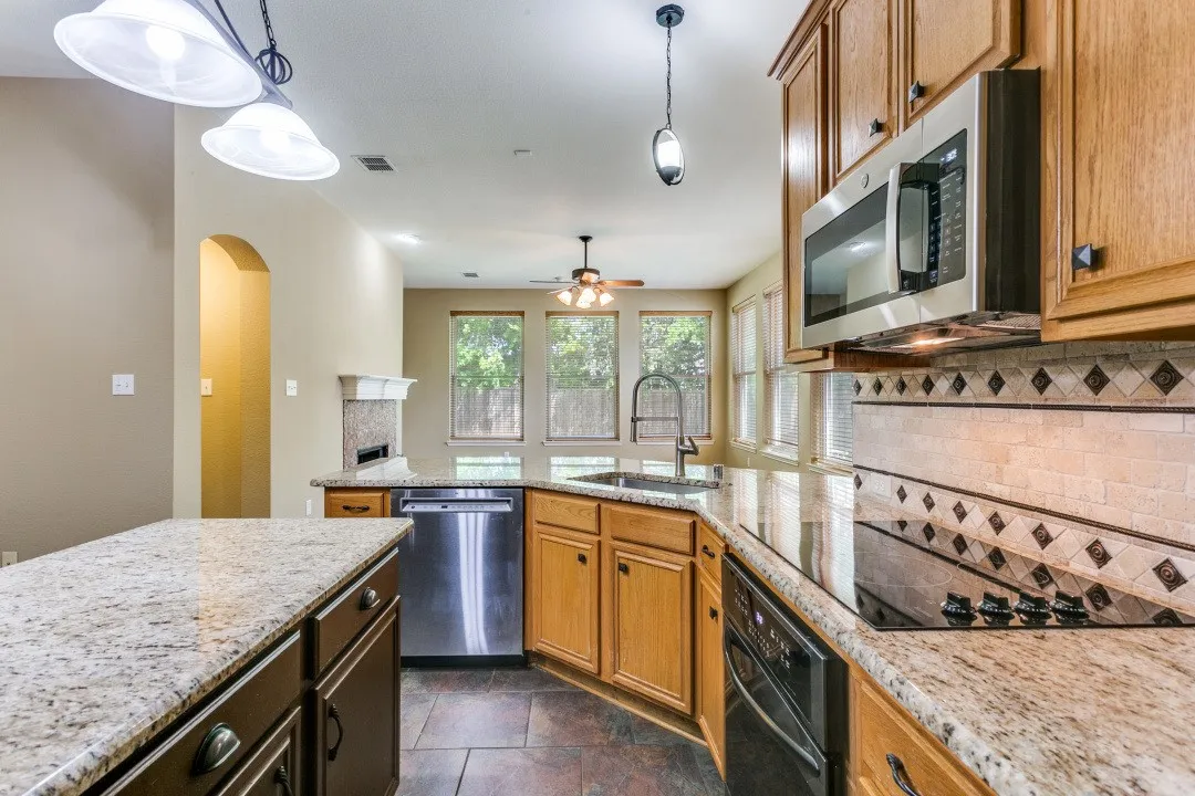 Kitchen featuring black appliances, a peninsula, light stone counters, arched walkways, and ceiling fan