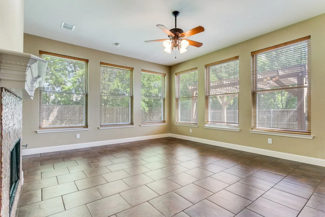 Unfurnished living room featuring a ceiling fan, a stone fireplace, and plenty of natural light
