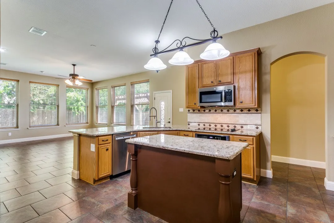 Kitchen with a peninsula, a kitchen island, wood finish cabinetry, and arched walkways