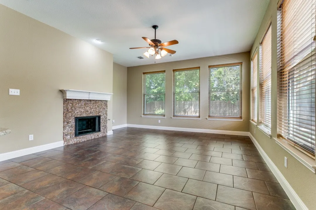 Unfurnished living room with a ceiling fan and a tile fireplace. Notice all this natural light.