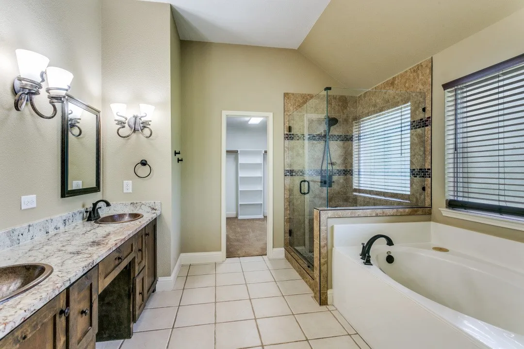 Bathroom featuring double vanity, a shower stall, a garden tub, light tile patterned floors, and a walk in closet