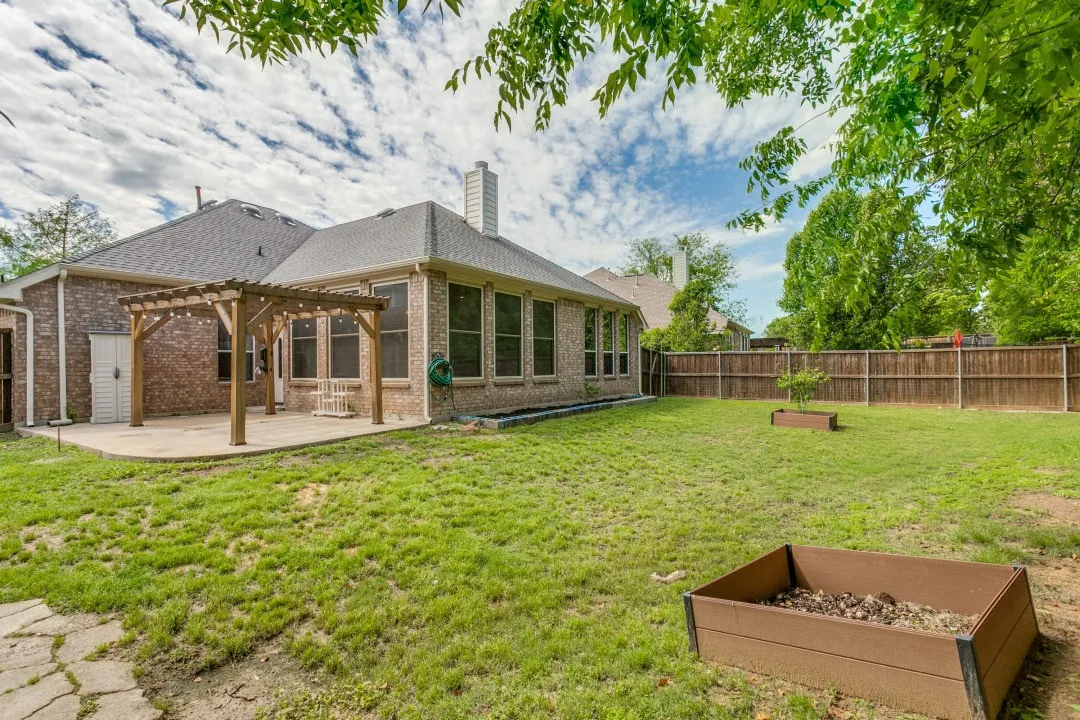 Back of property featuring a chimney, a pergola, a fenced backyard, a patio area, and brick siding