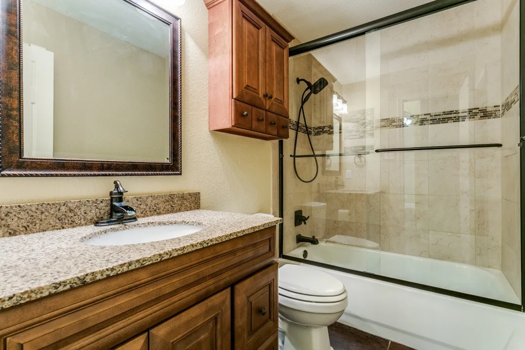 Full bathroom featuring vanity, combined bath / shower with glass door, and a textured wall