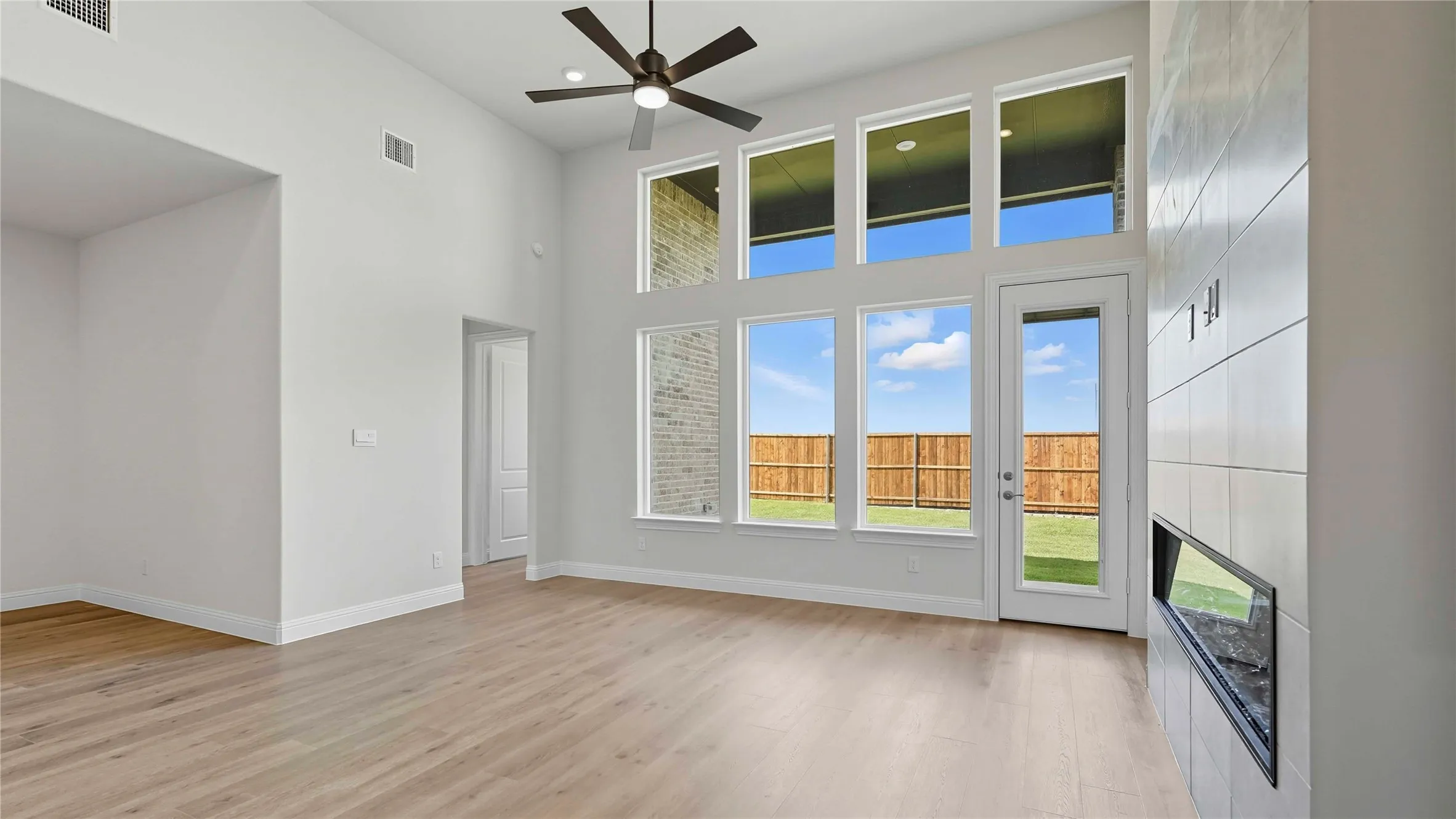 Unfurnished living room featuring a high ceiling, ceiling fan, and light wood finished floors