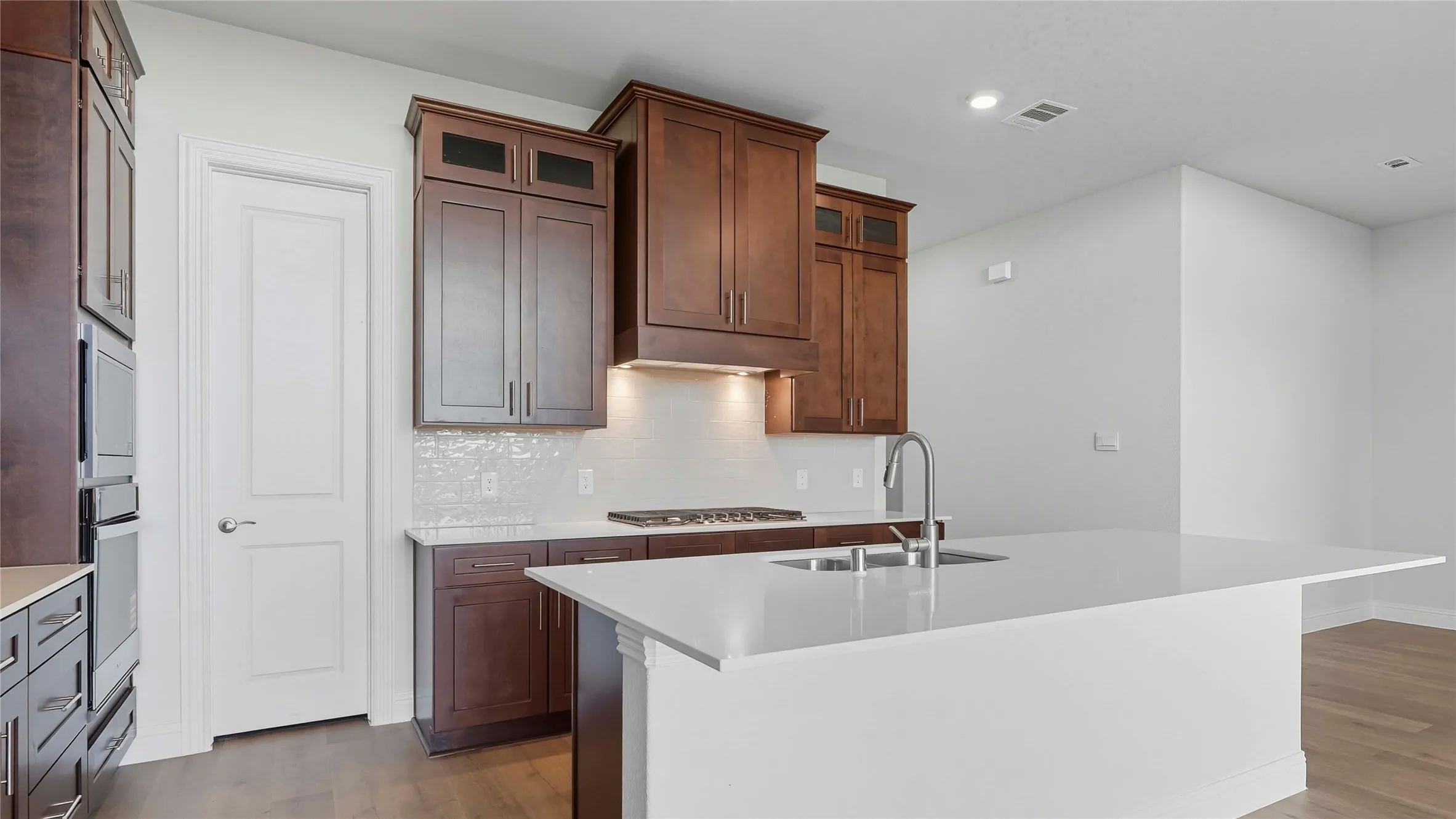 Kitchen with a center island with sink, dark wood-style floors, light stone counters, tasteful backsplash, and stainless steel appliances