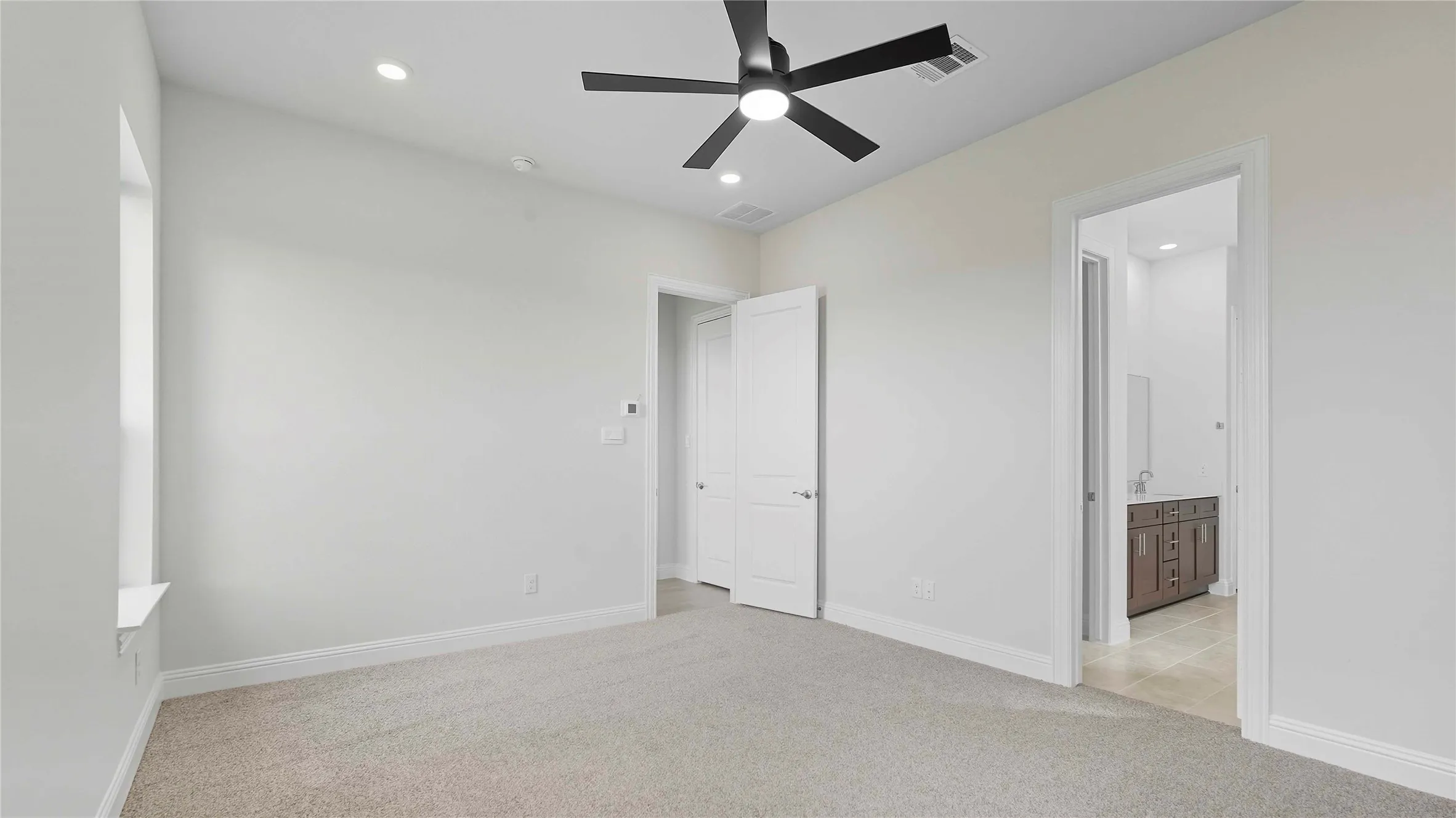 Unfurnished bedroom with light carpet, recessed lighting, ceiling fan, and ensuite bath