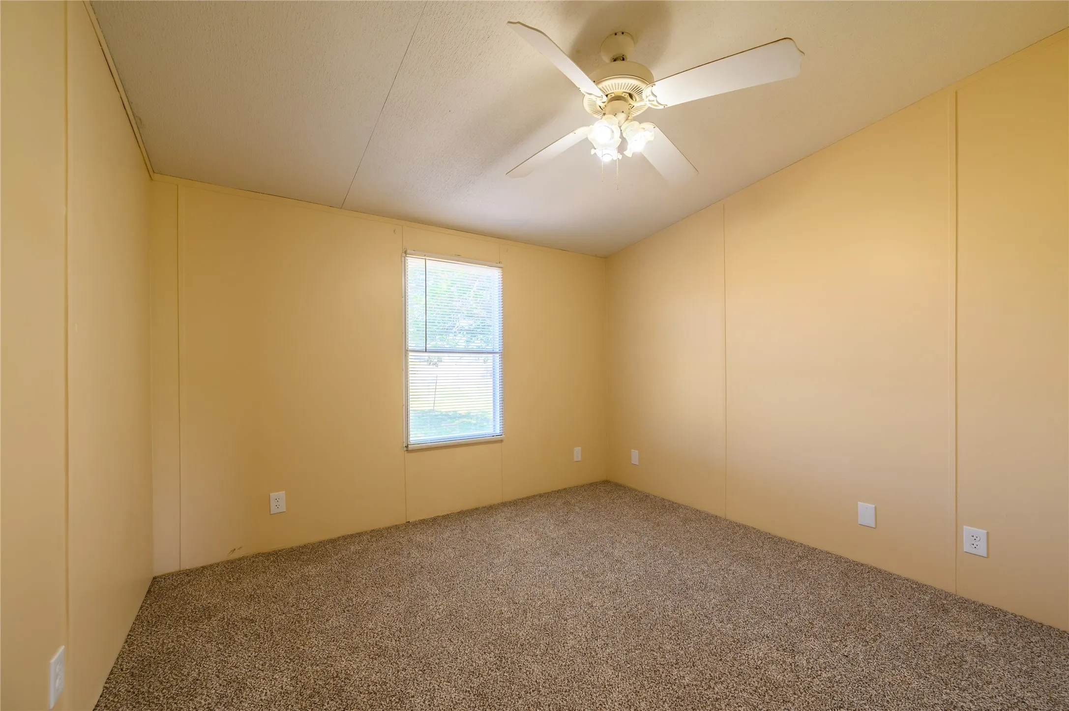 Carpeted spare room featuring a decorative wall, ceiling fan, and lofted ceiling