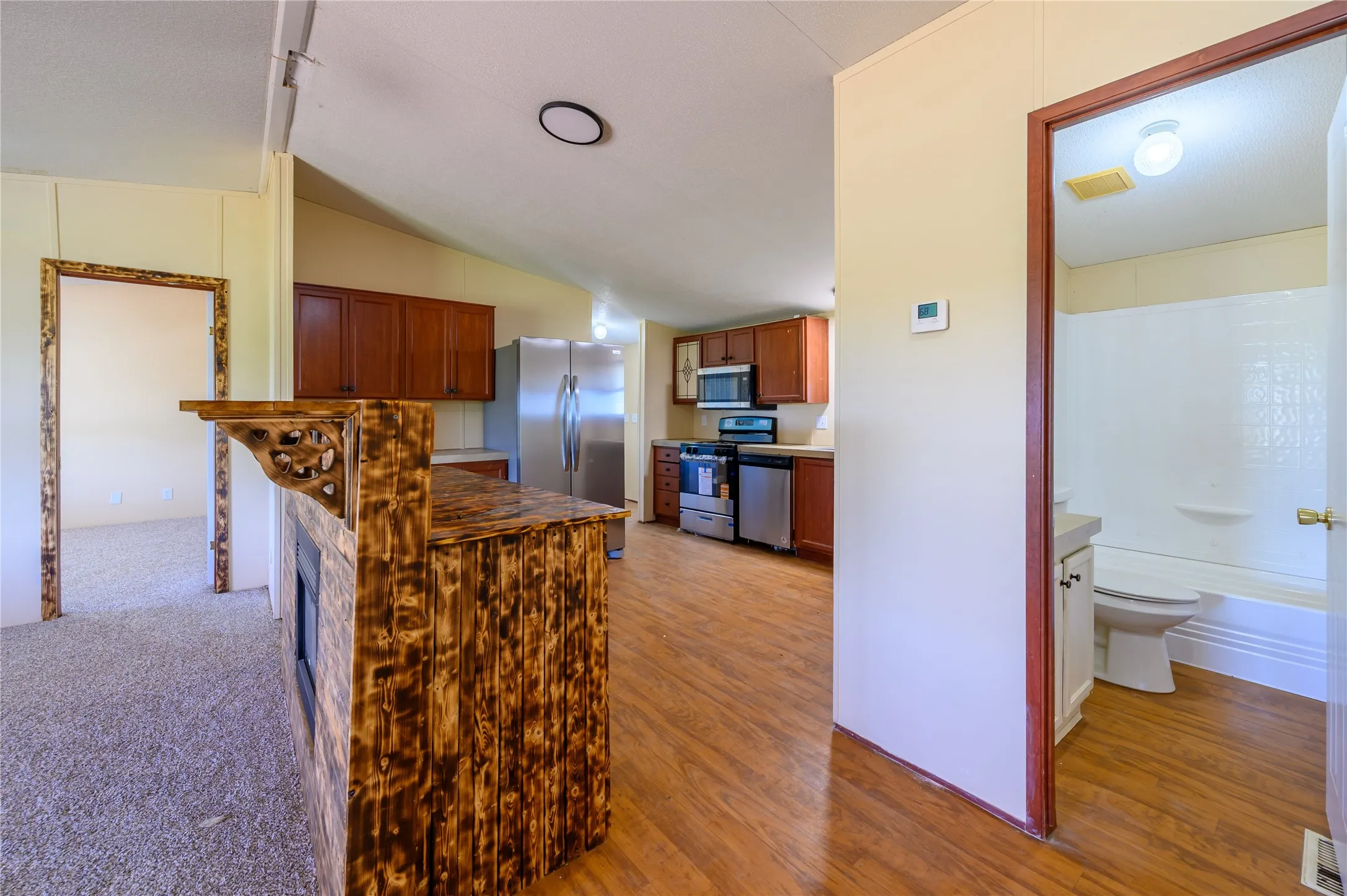 Kitchen featuring wood finish cabinetry, stainless steel appliances, and vaulted ceiling