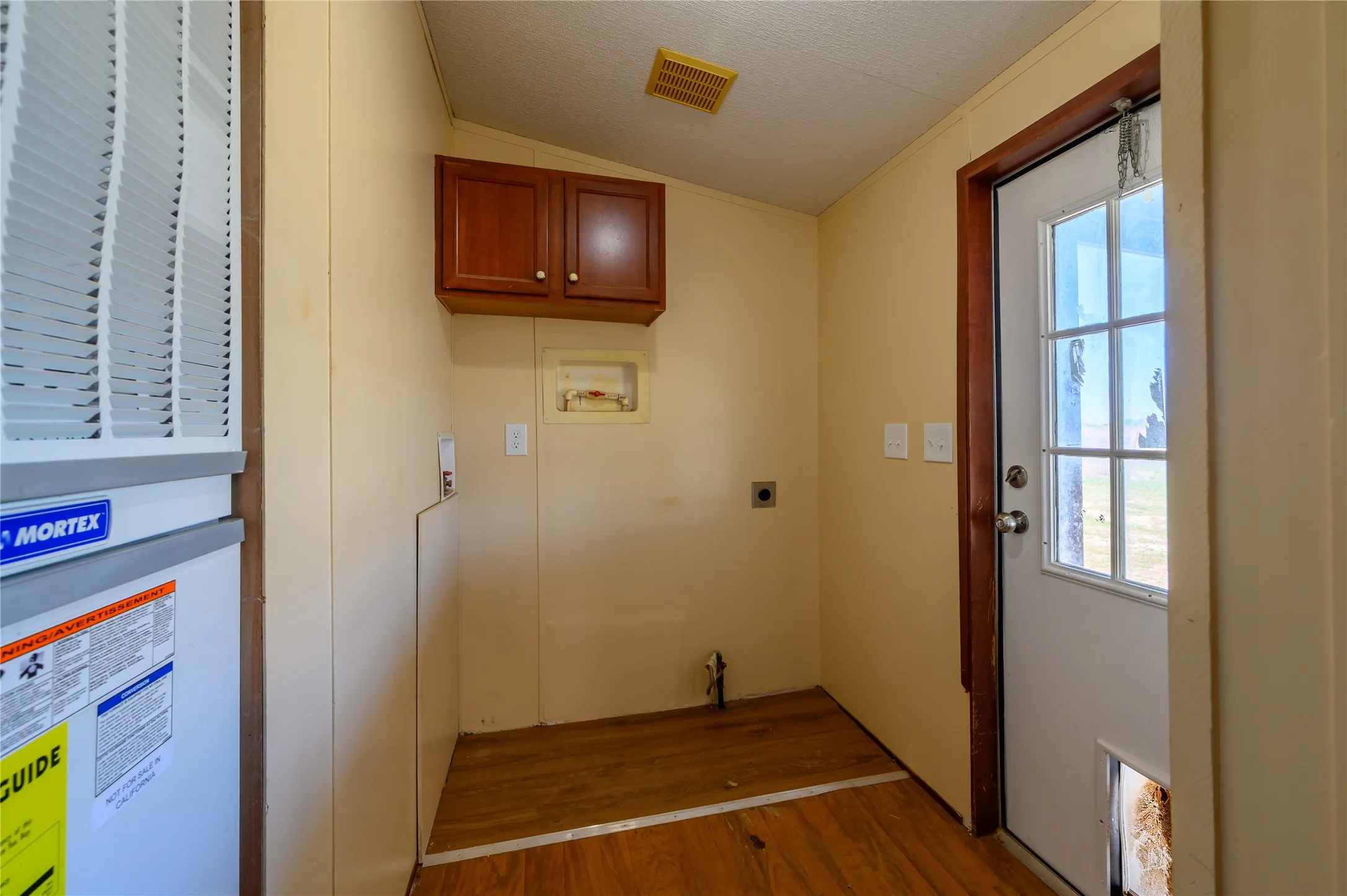 Laundry area featuring washer hookup, cabinet space, wood finished floors, a heating unit, and vaulted ceiling