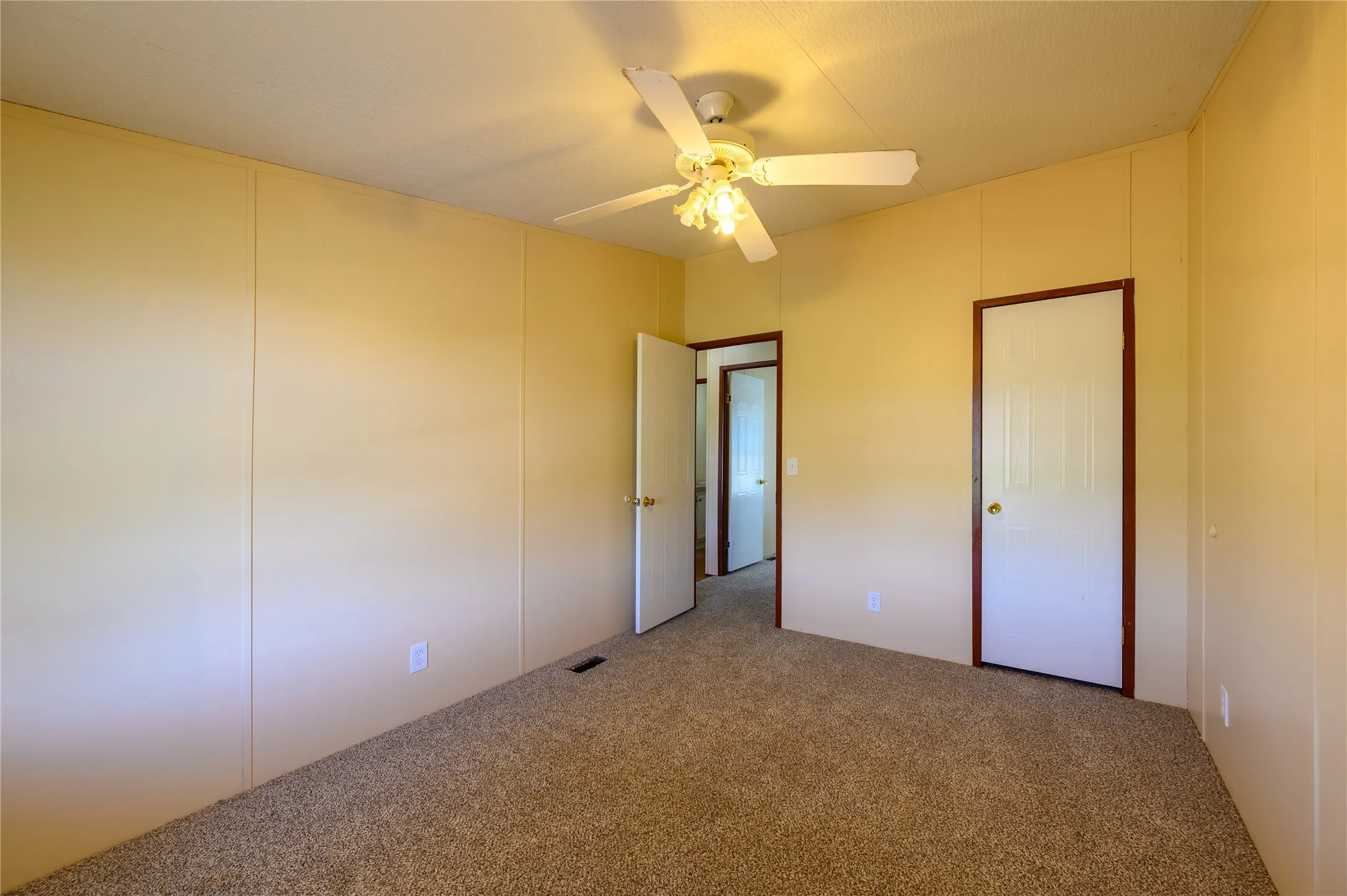 Unfurnished bedroom with carpet floors, ceiling fan, and a decorative wall