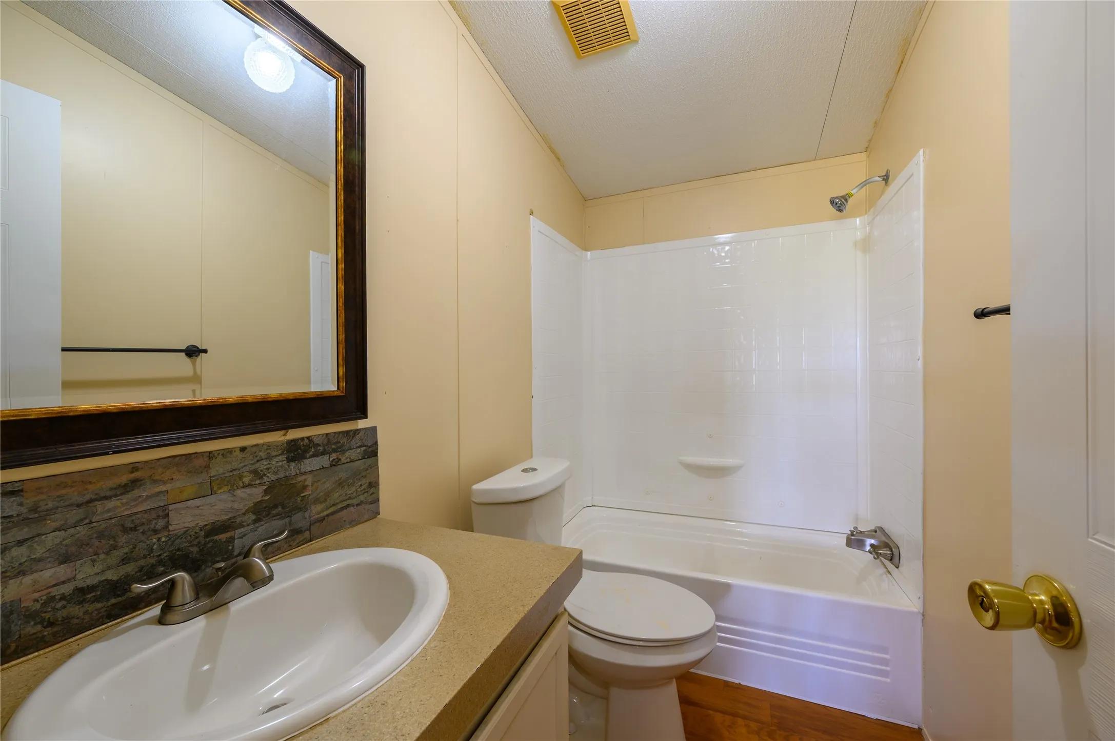 Bathroom with vanity,  shower combination, decorative backsplash, a textured ceiling, and dark wood finished floors
