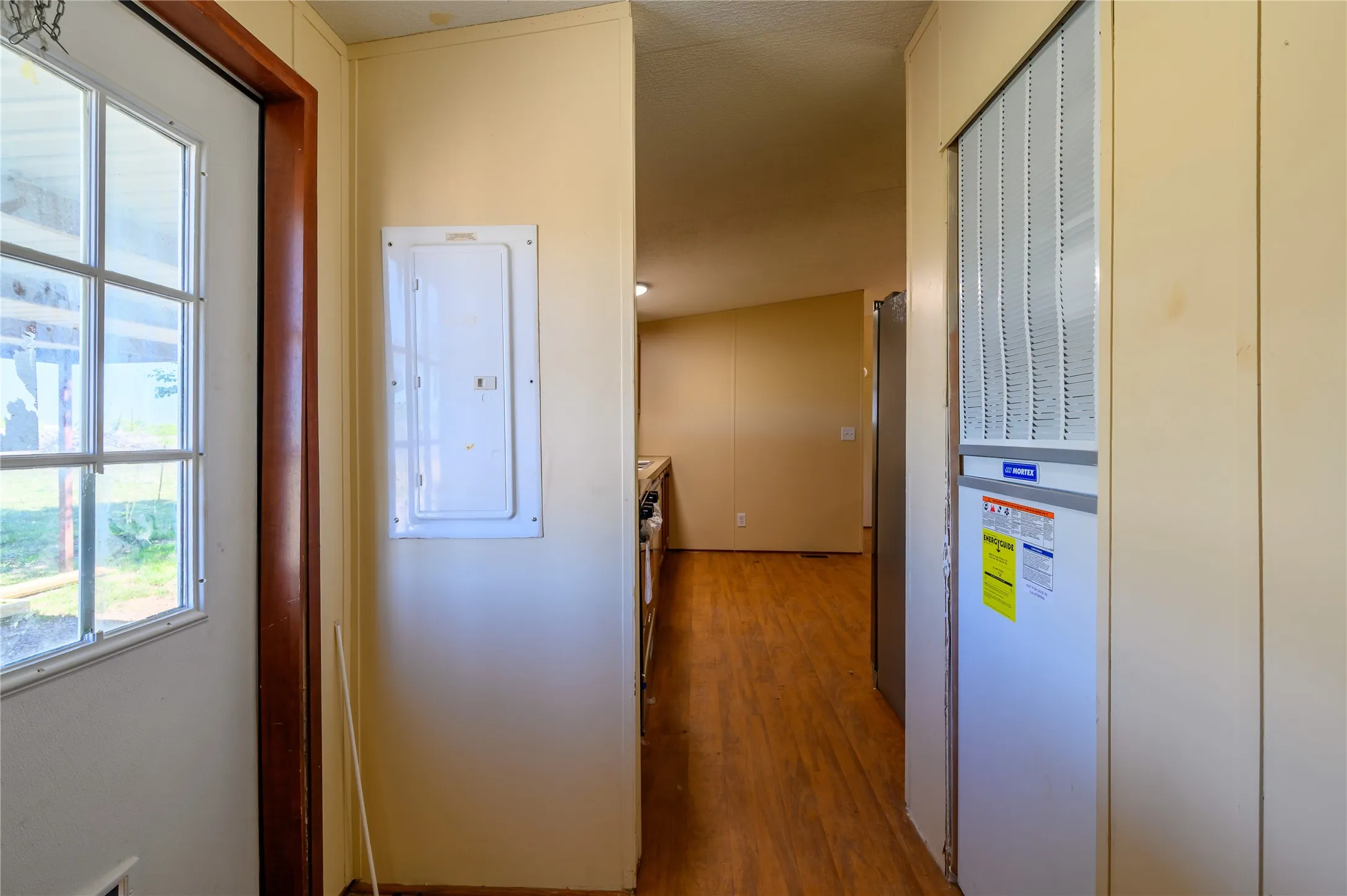 Corridor with electric panel, a heating unit, and light wood finished floors
