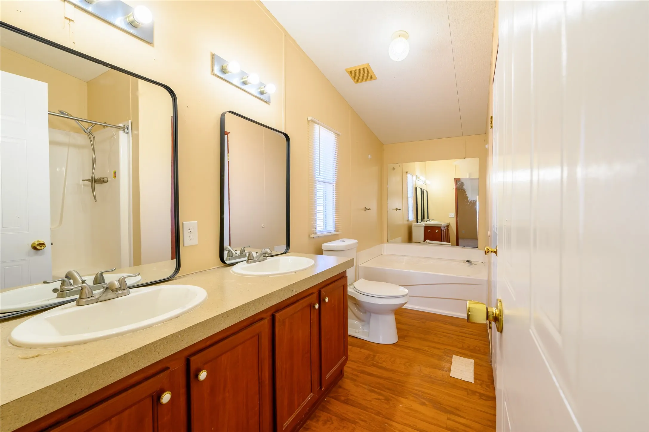 Full bathroom with a garden tub, double vanity, a shower with shower curtain, and dark wood-type flooring