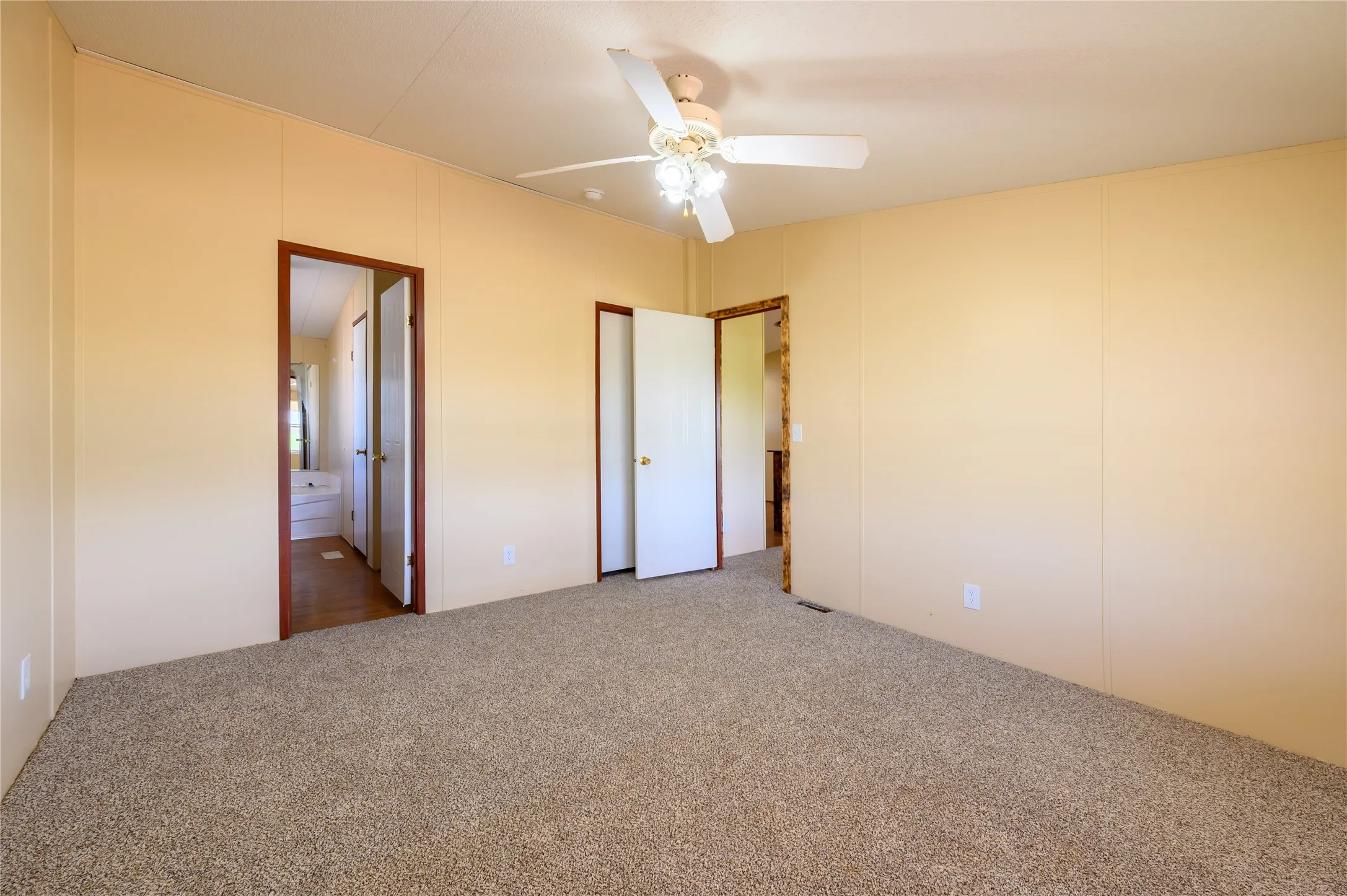 Unfurnished bedroom featuring carpet, ceiling fan, and ensuite bathroom