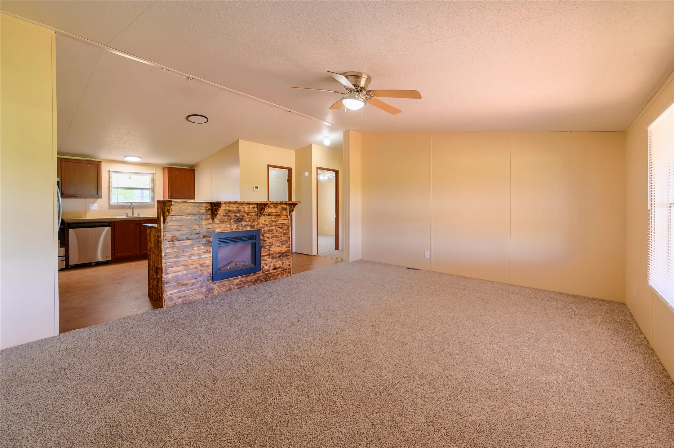 Unfurnished living room featuring light carpet, ceiling fan, and a fireplace
