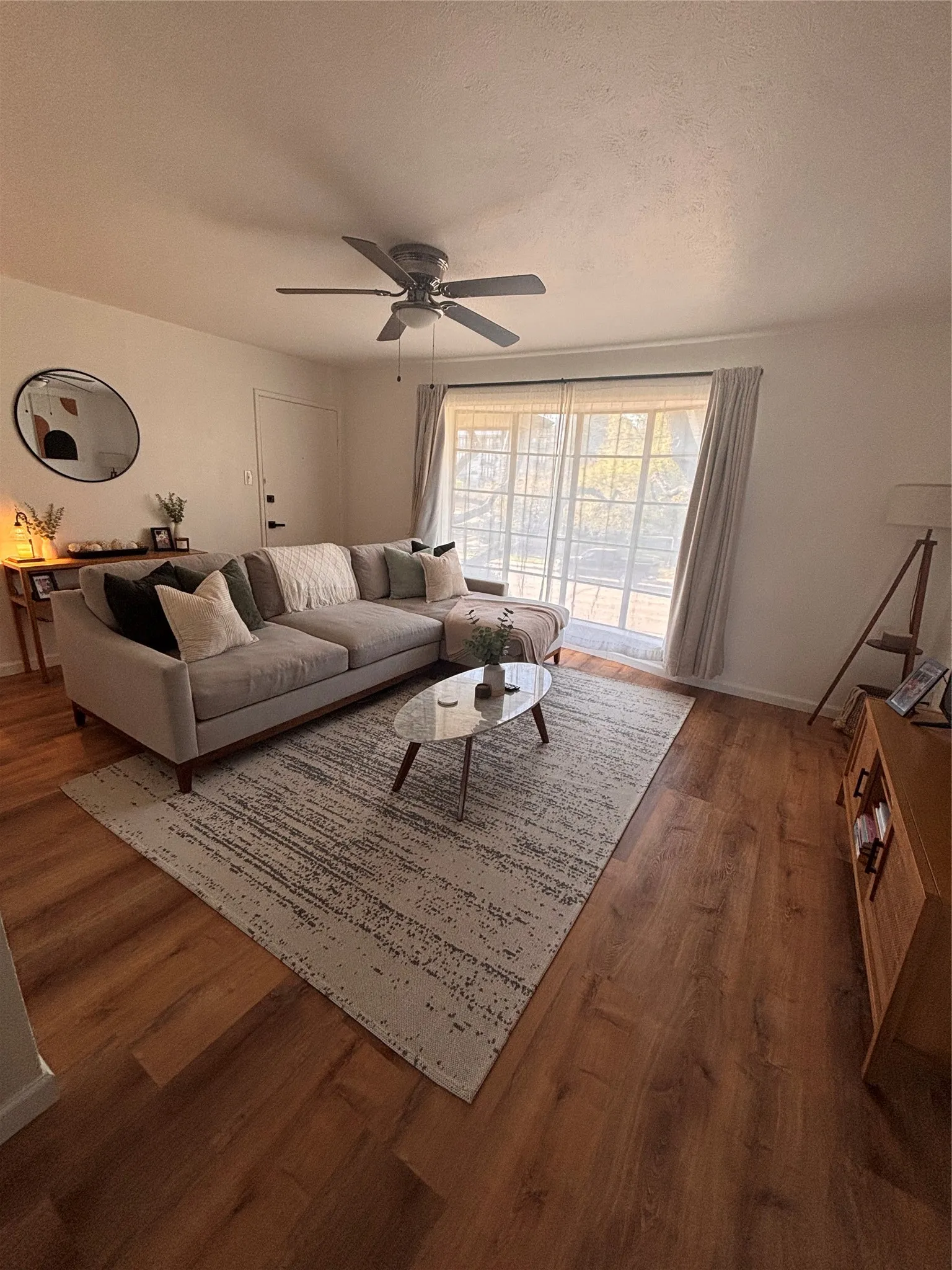 Living area featuring a ceiling fan, dark wood-style flooring, and a textured ceiling