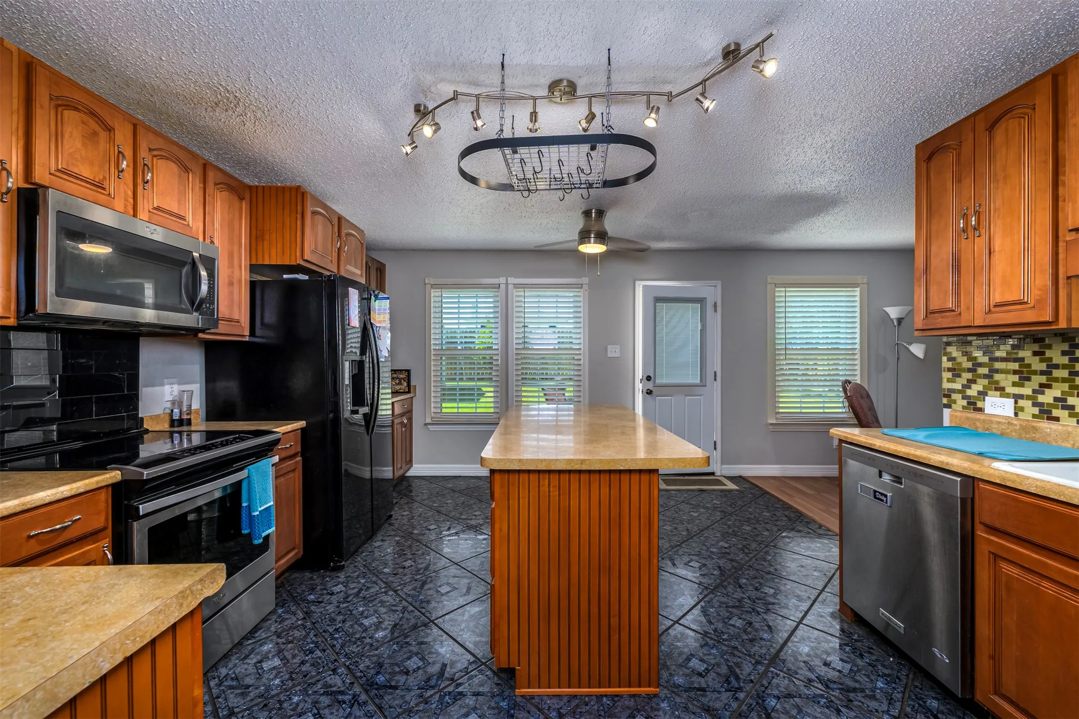 Kitchen featuring backsplash, wood finish cabinets, a kitchen island, and a textured ceiling