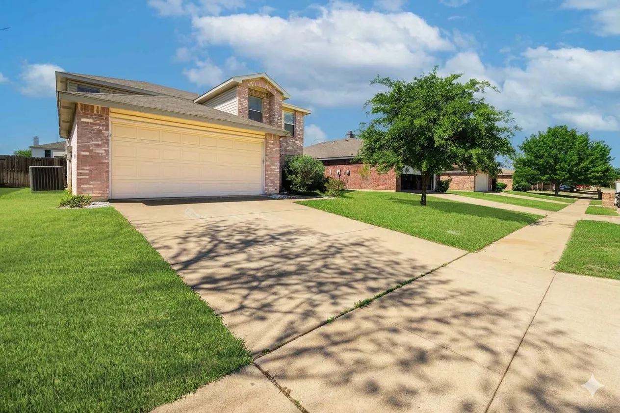View of front of house with an attached garage, driveway, and brick siding