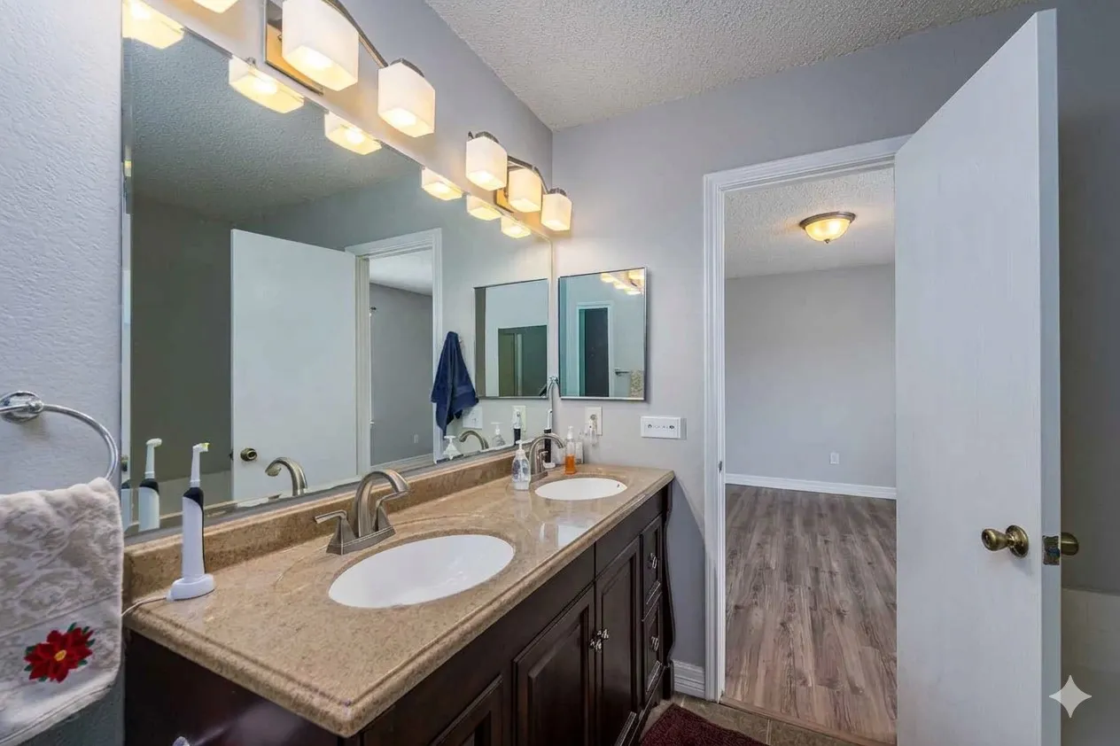 Bathroom with a textured ceiling, double vanity, and wood finished floors