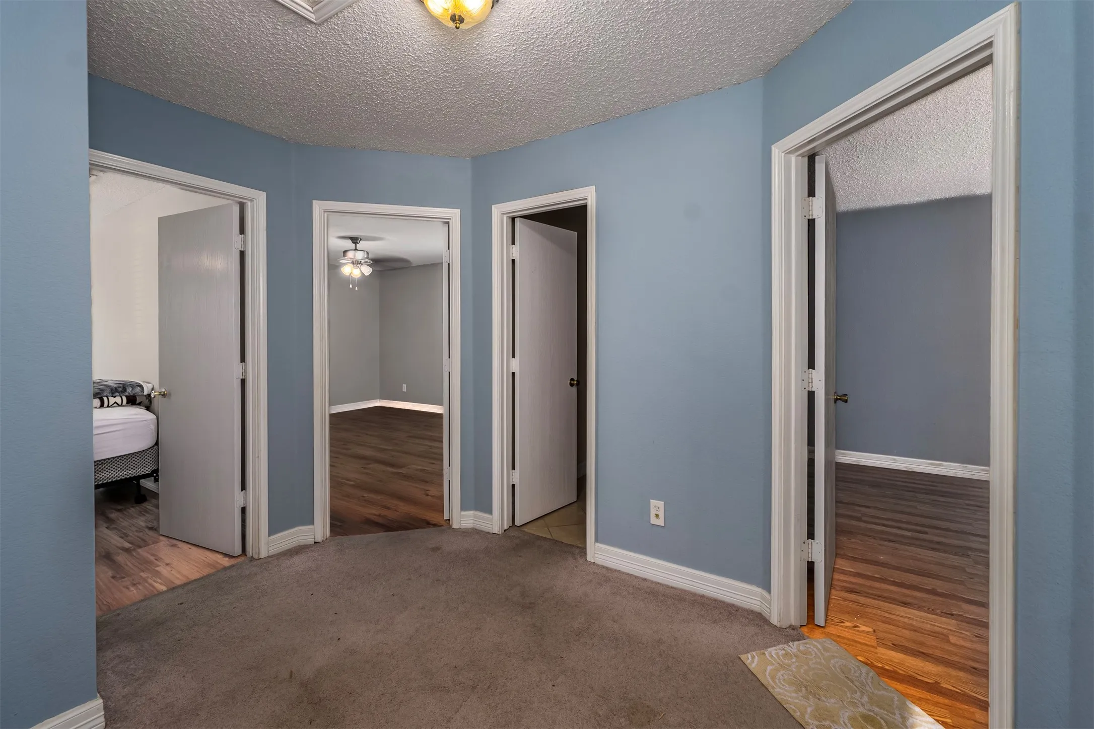 Bedroom with light colored carpet, a textured ceiling, and light wood-type flooring