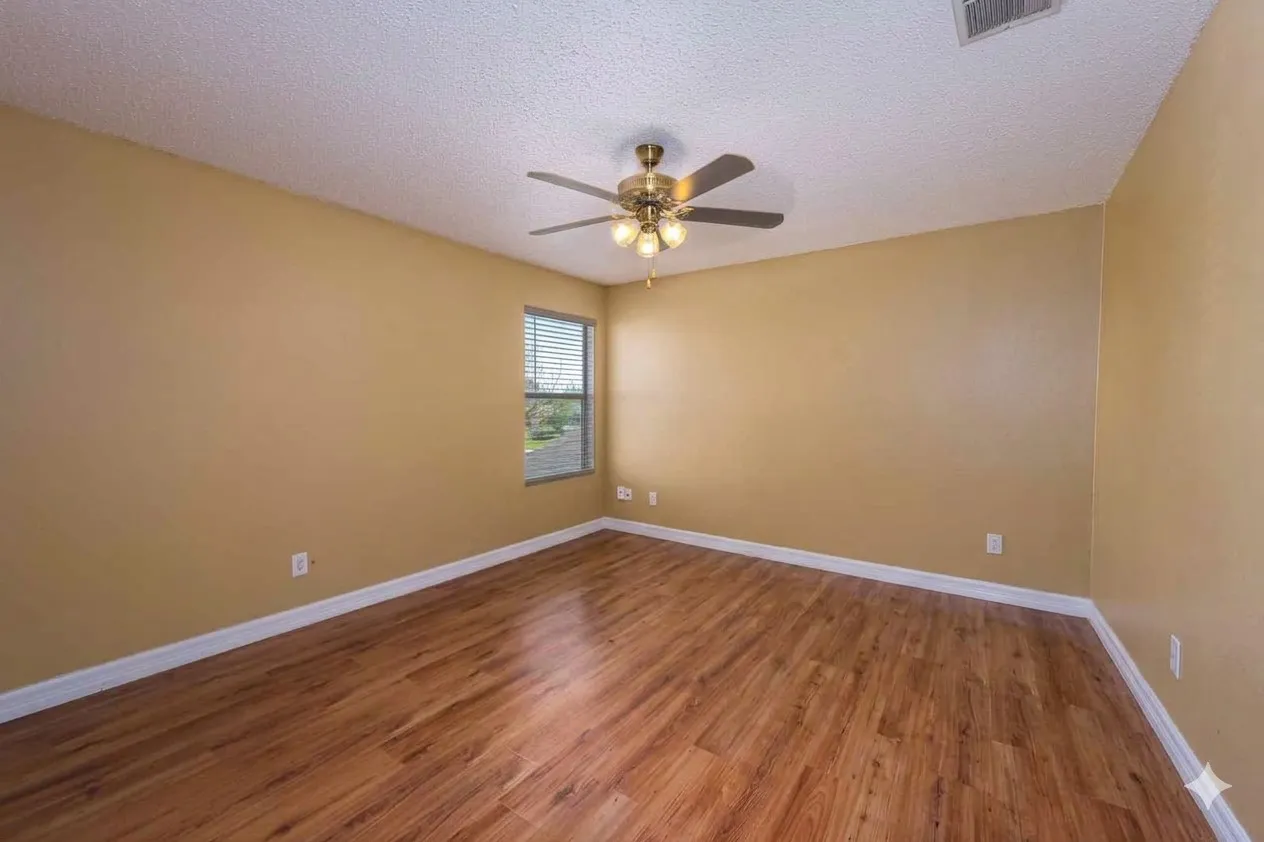 Empty room with a textured ceiling, dark wood finished floors, and a ceiling fan
