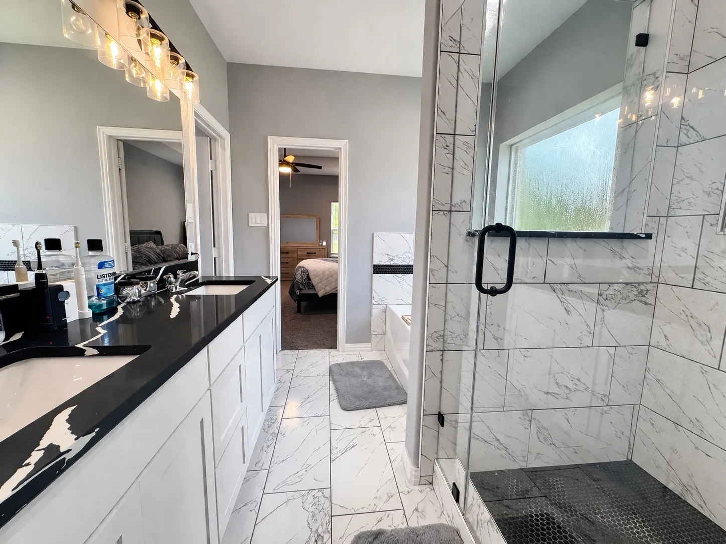 Full bath featuring ensuite bath, light marble finish floors, double vanity, a shower stall, and ceiling fan