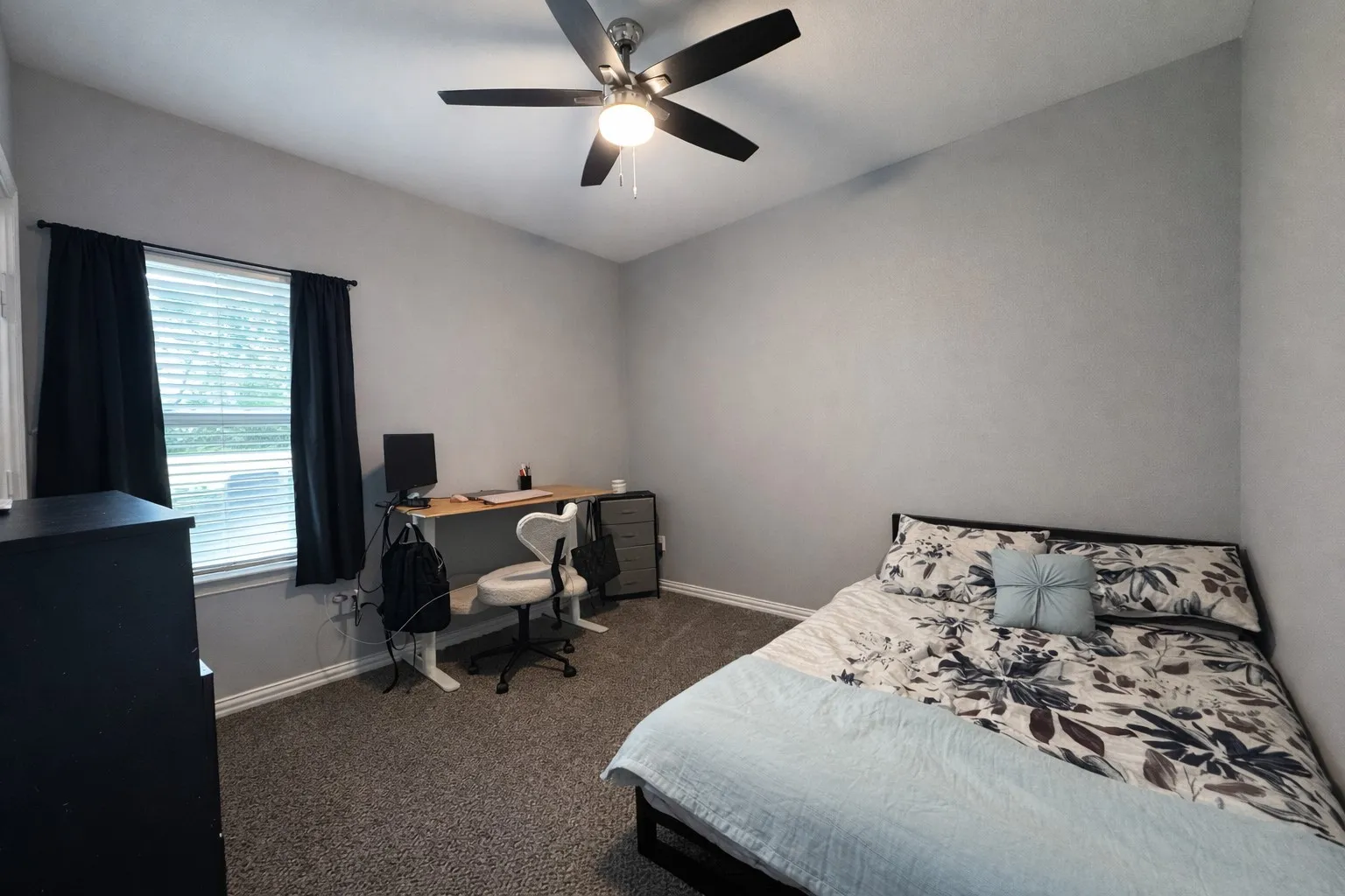 Bedroom with dark carpet, a desk, and ceiling fan